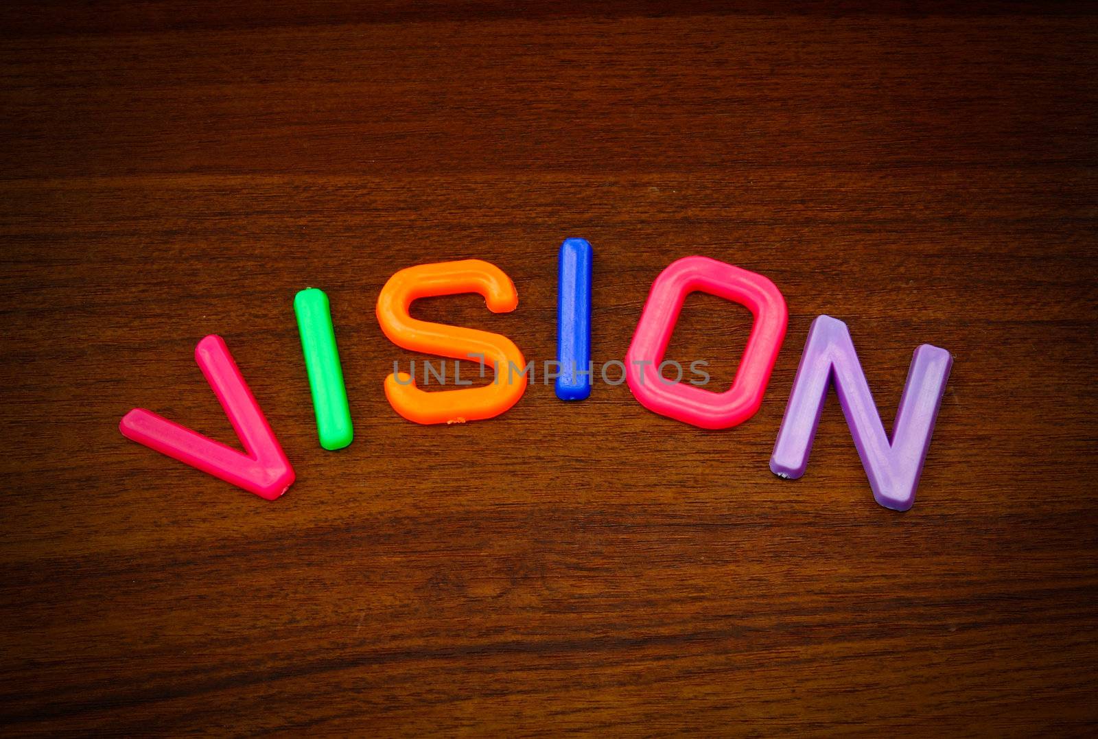 Vision in colorful toy letters on wood background