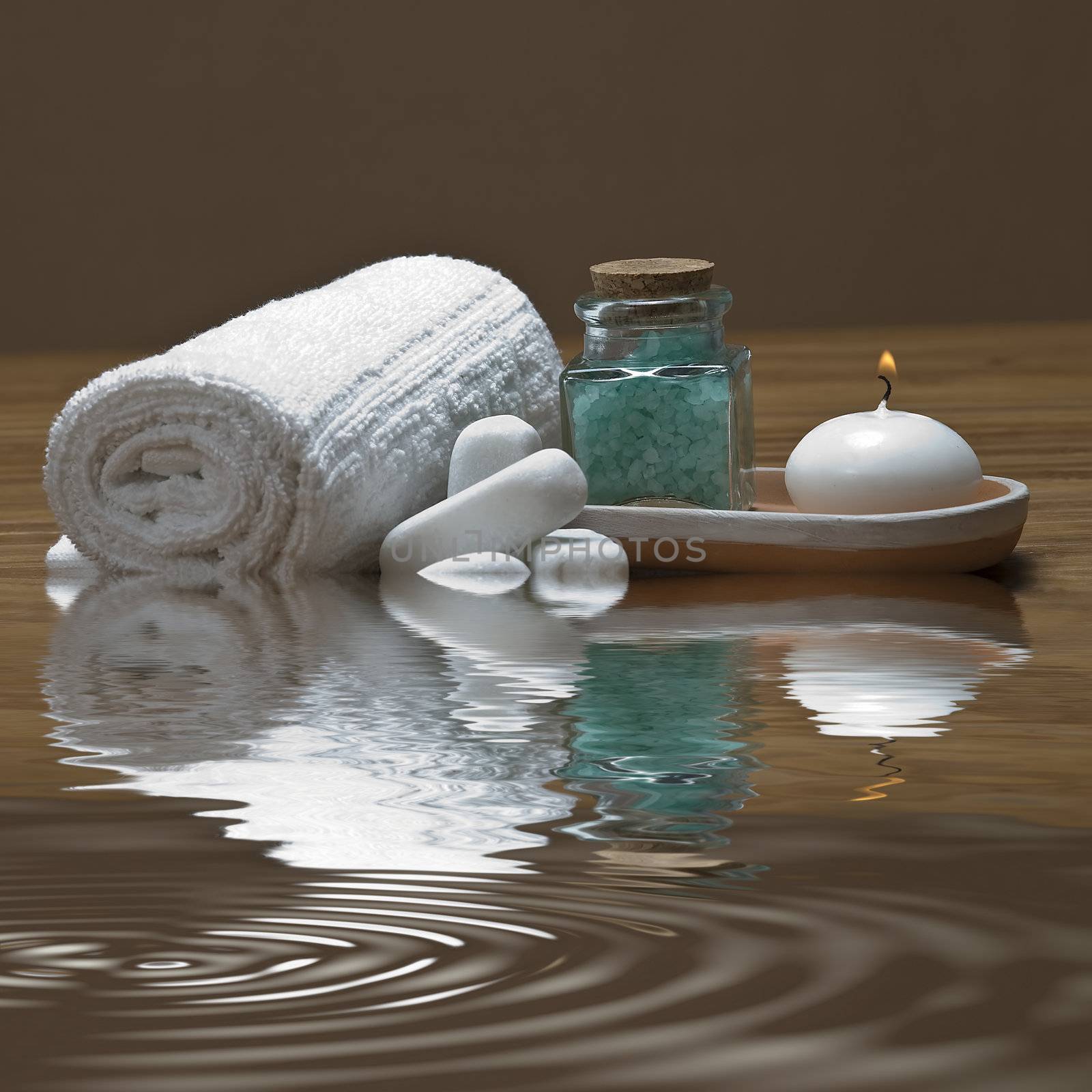 Spa background with bath salts, towels and candles on a bamboo mat.