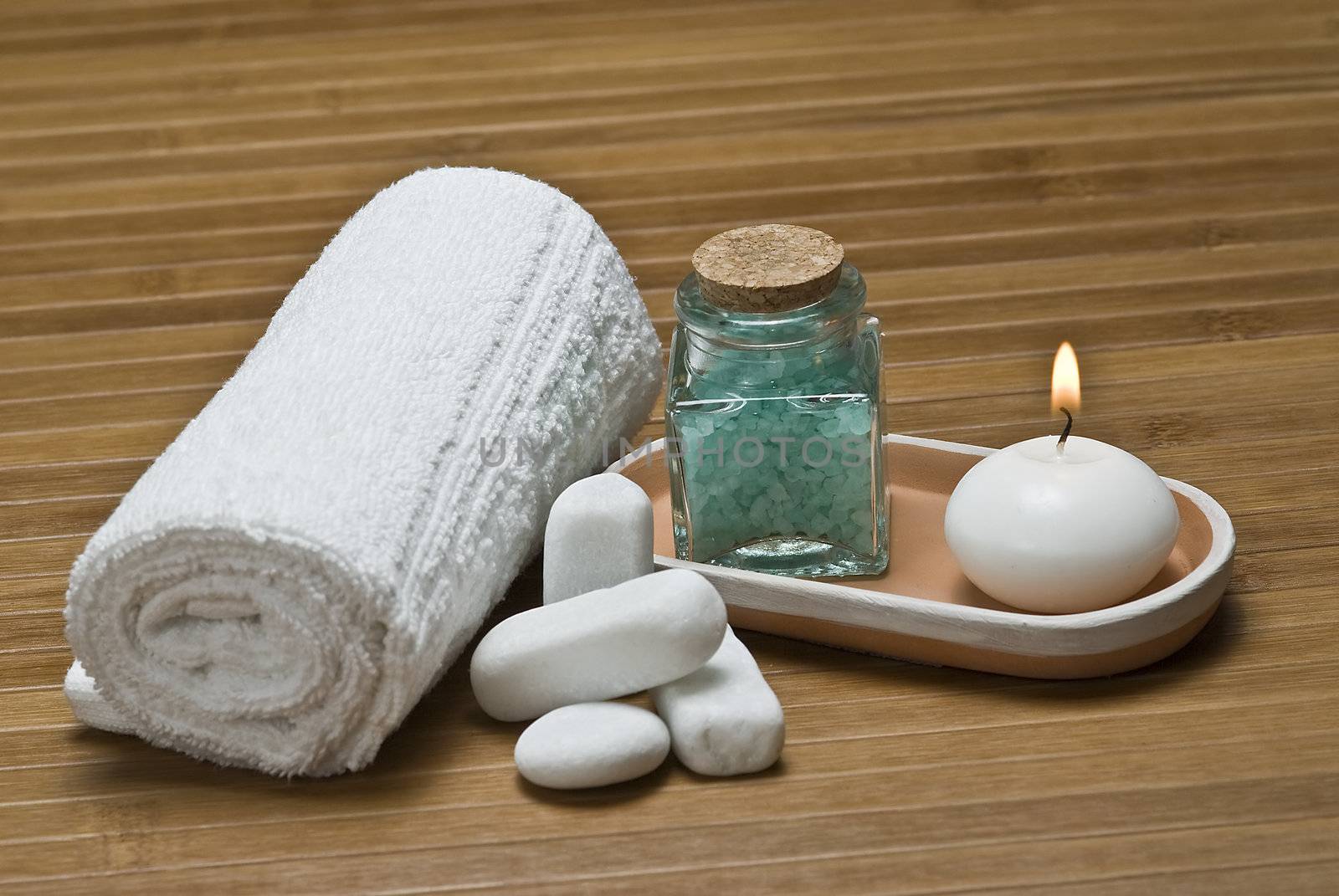 Spa background with bath salts, towels and candles on a bamboo mat.