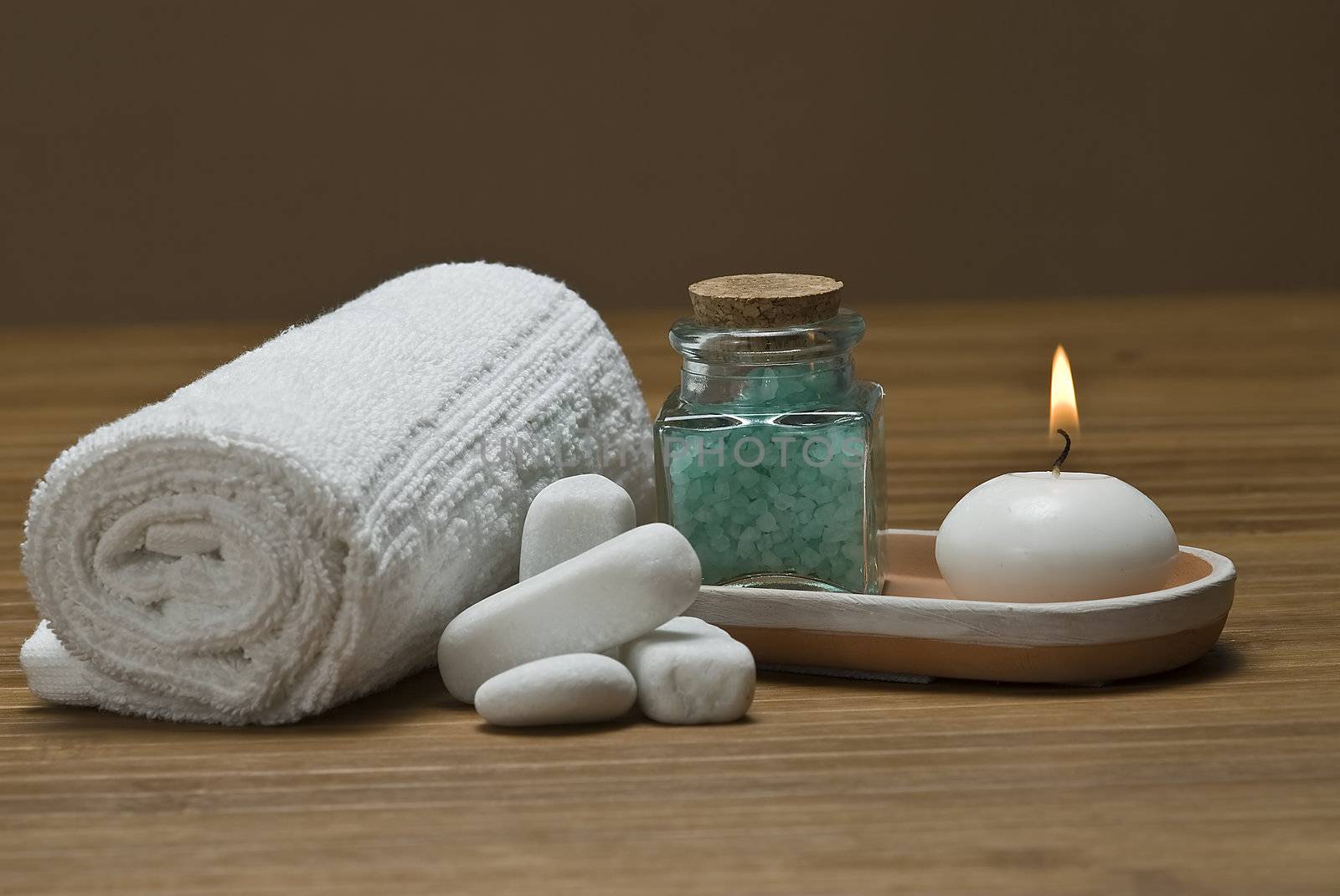 Spa background with bath salts, towels and candles on a bamboo mat.