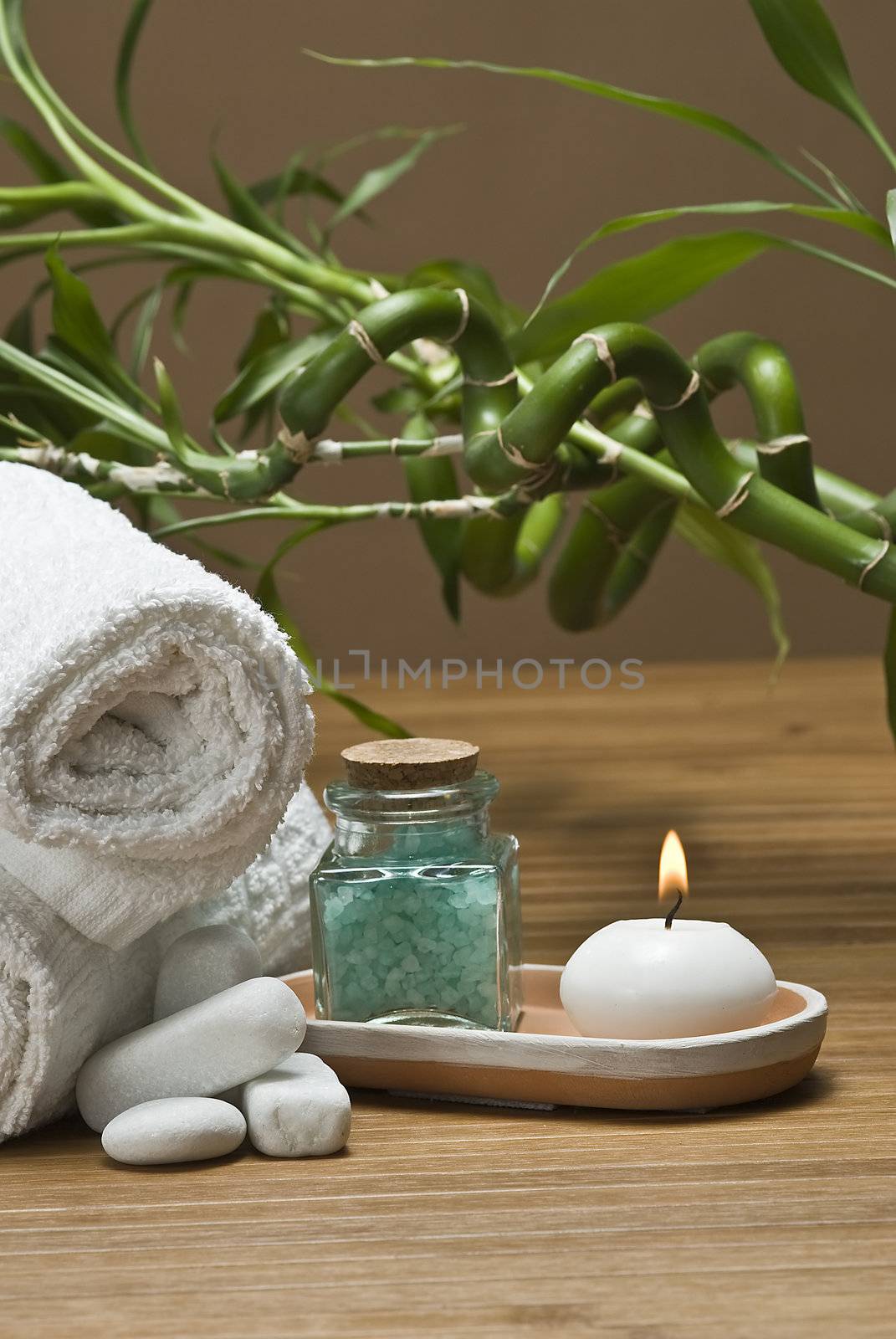 Spa background with bath salts, towels and candles on a bamboo mat.