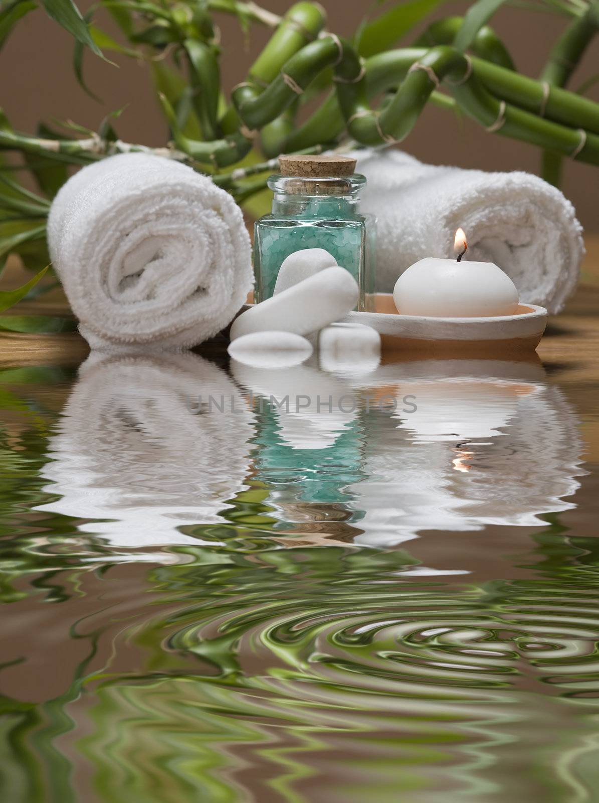 Spa background with bath salts, towels and candles on a bamboo mat.