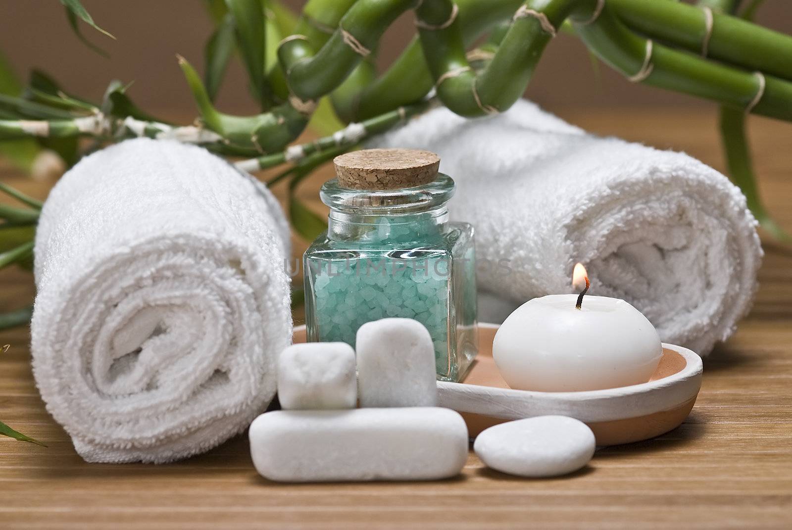 Spa background with bath salts, towels and candles on a bamboo mat.