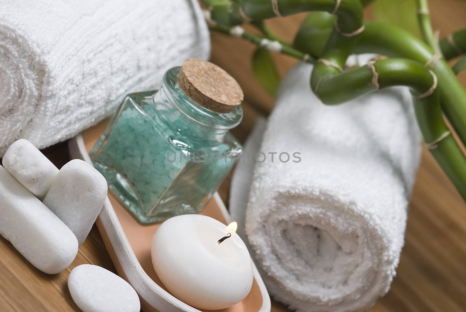 Spa background with bath salts, towels and candles on a bamboo mat.