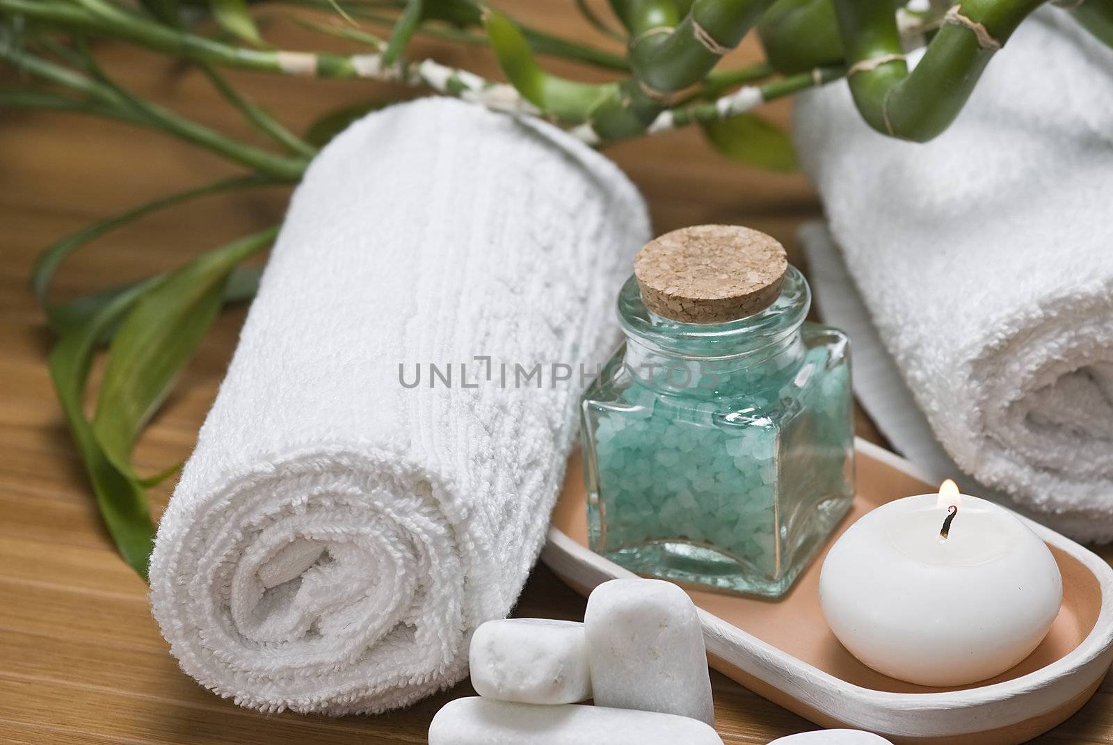 Spa background with bath salts, towels and candles on a bamboo mat.