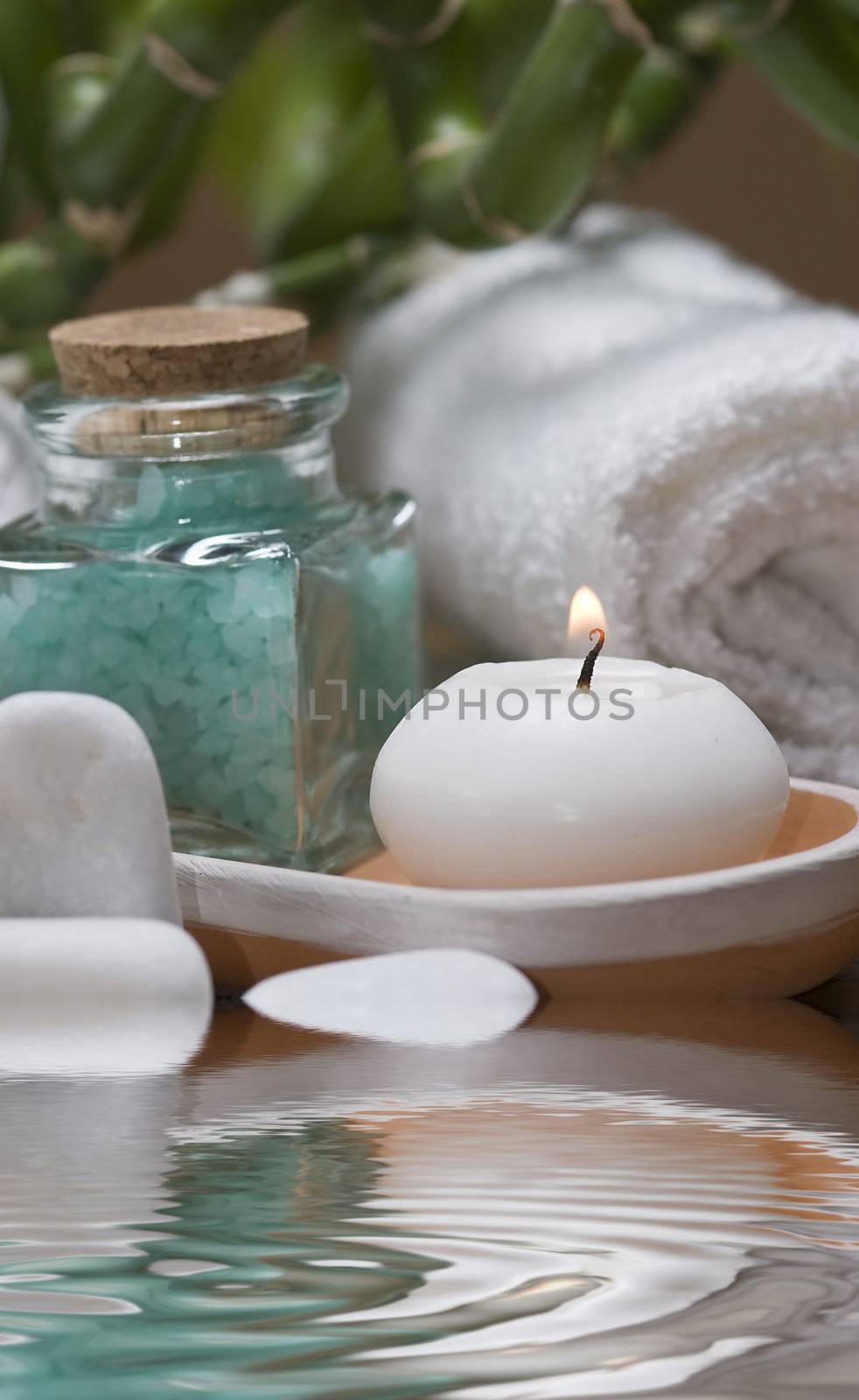 Spa background with bath salts, towels and candles on a bamboo mat.