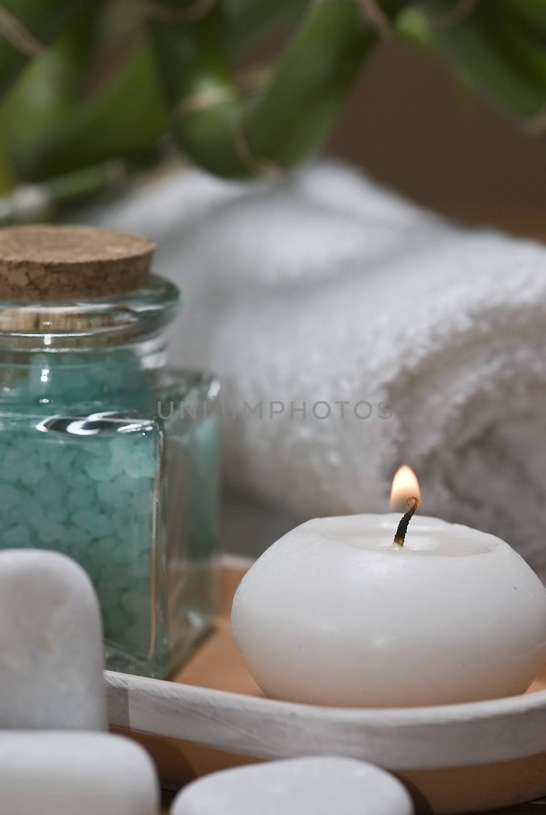 Spa background with bath salts, towels and candles on a bamboo mat.