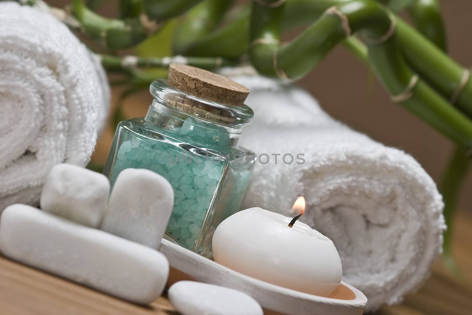 Spa background with bath salts, towels and candles on a bamboo mat.