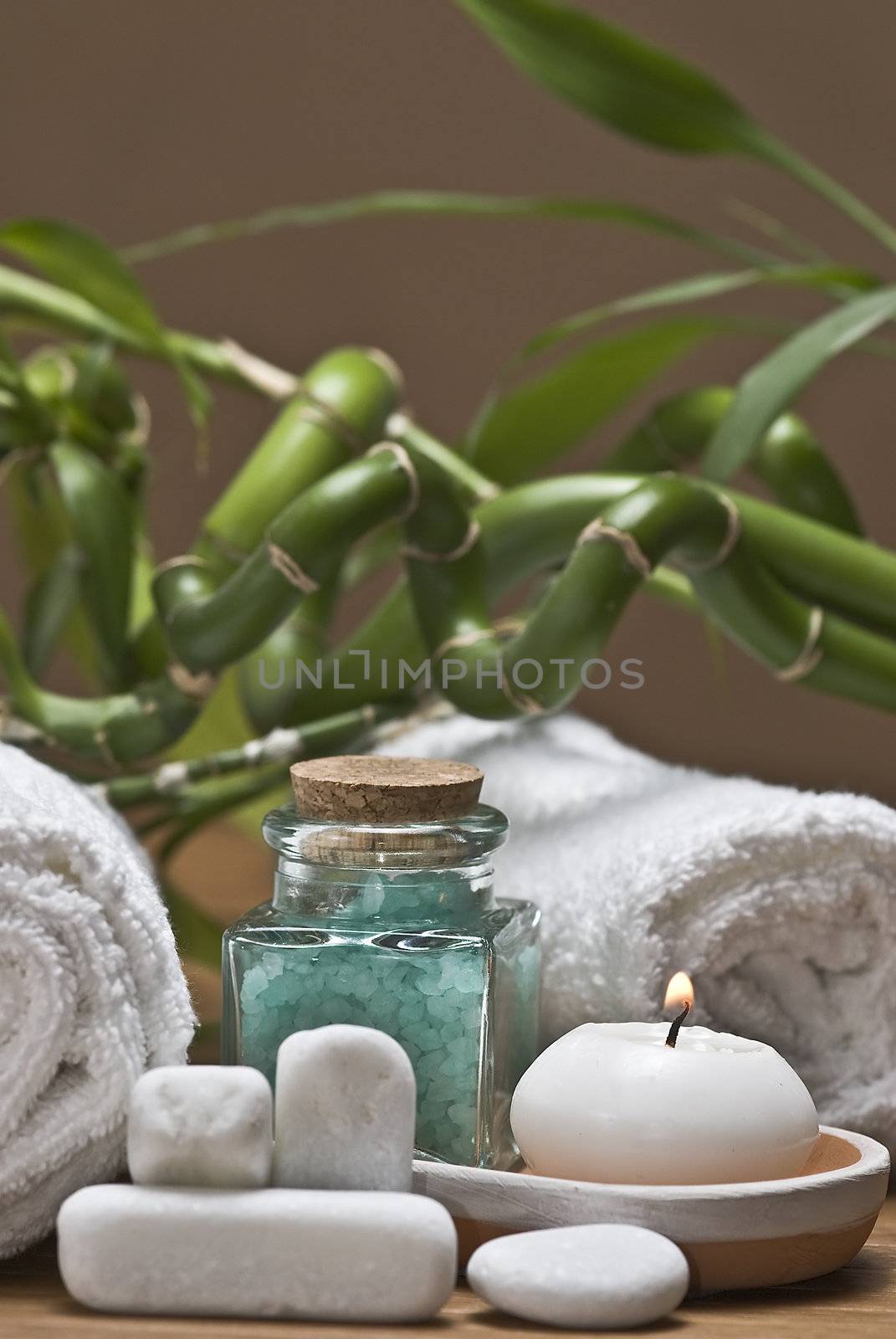 Spa background with bath salts, towels and candles on a bamboo mat.