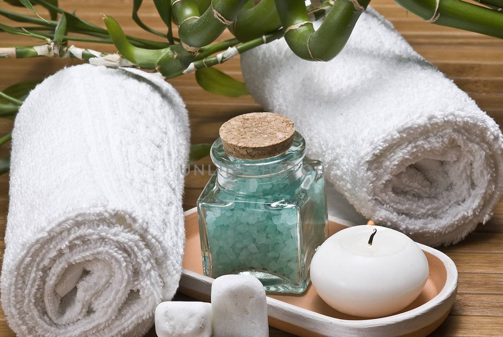 Spa background with bath salts, towels and candles on a bamboo mat.