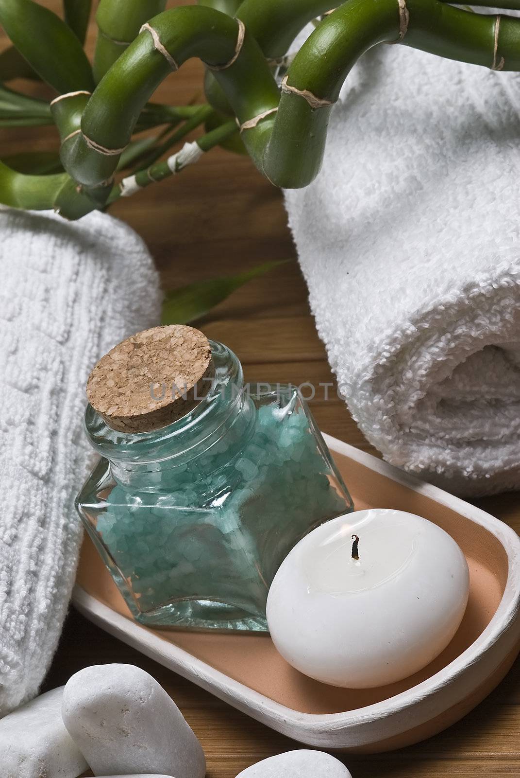 Spa background with bath salts, towels and candles on a bamboo mat.