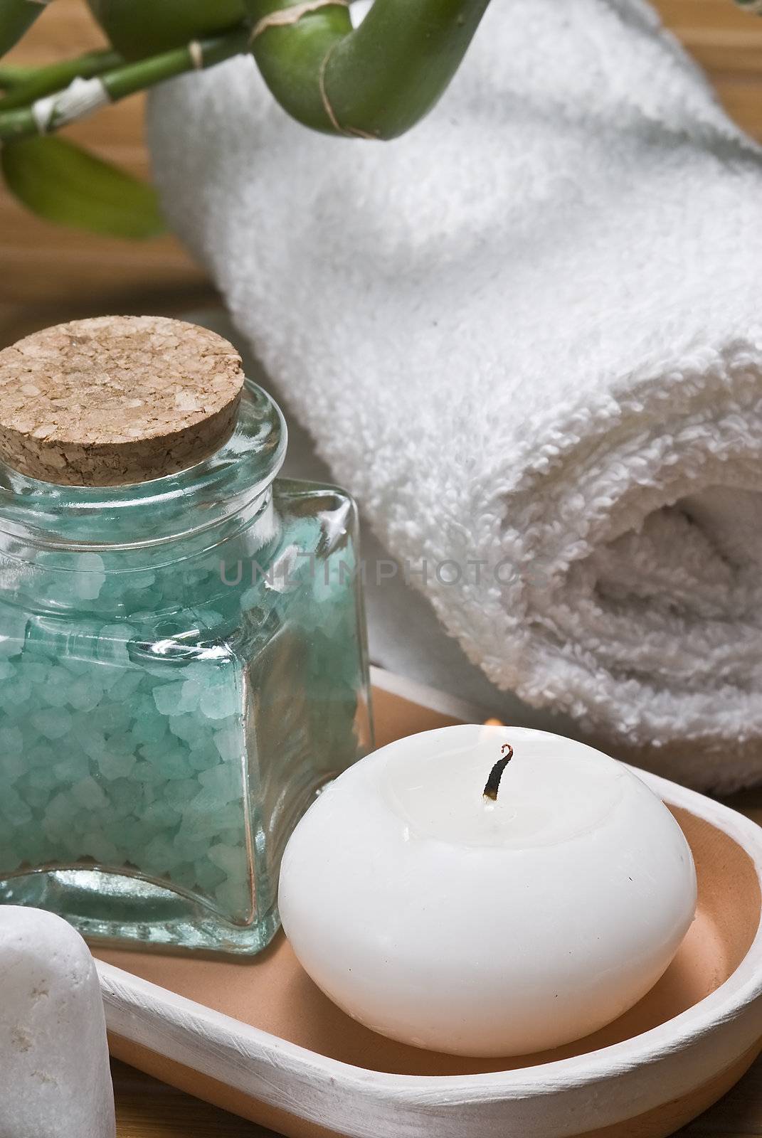 Spa background with bath salts, towels and candles on a bamboo mat.