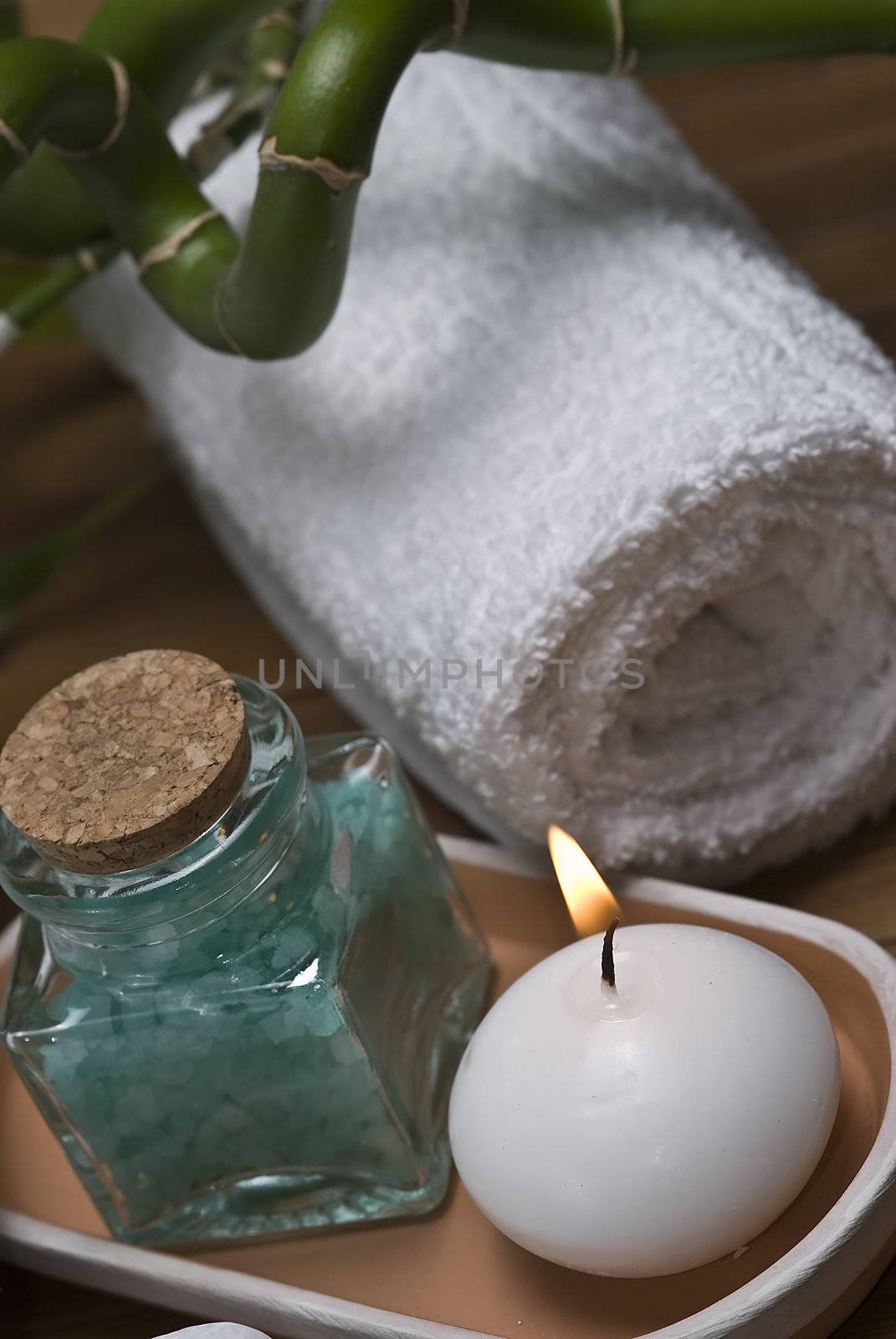 Spa background with bath salts, towels and candles on a bamboo mat.