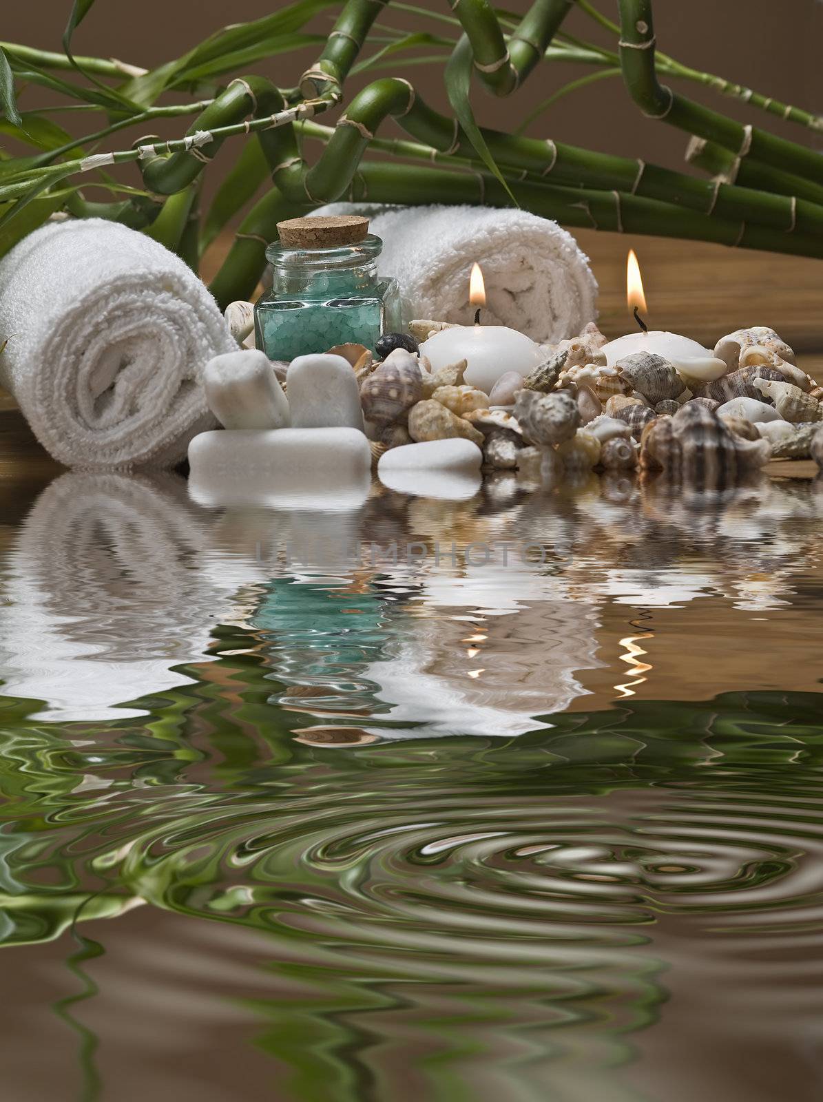 Spa background with bath salts, towels and candles on a bamboo mat.