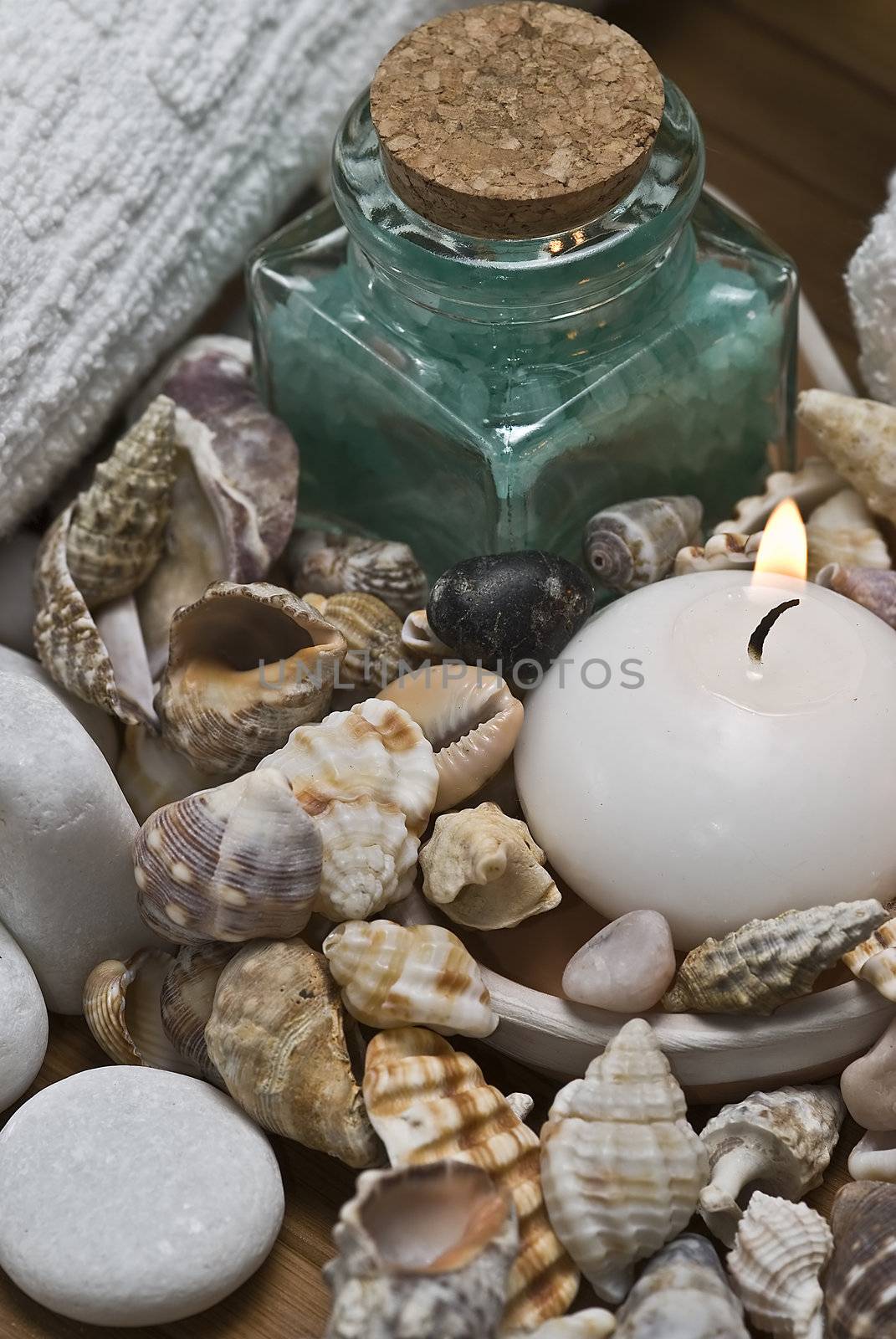 Spa background with bath salts, towels and candles on a bamboo mat.