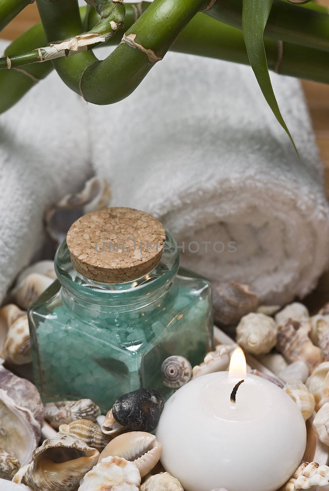 Spa background with bath salts, towels and candles on a bamboo mat.