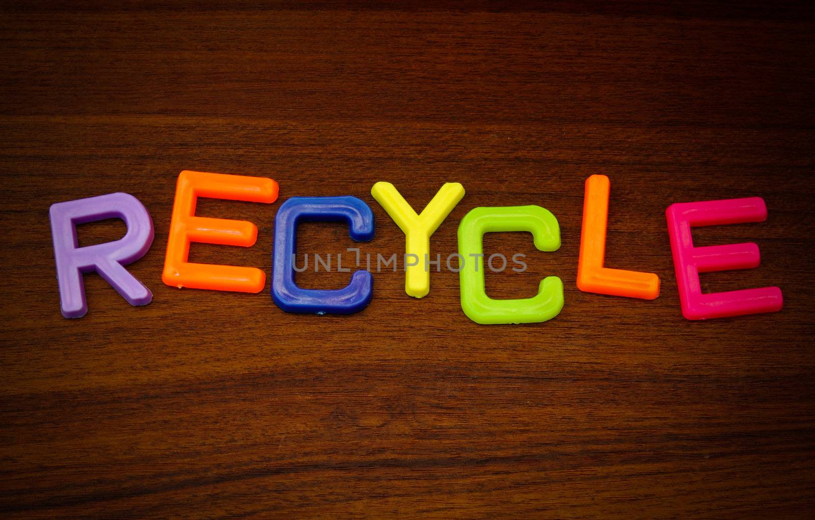 Recycle in colorful toy letters on wood background