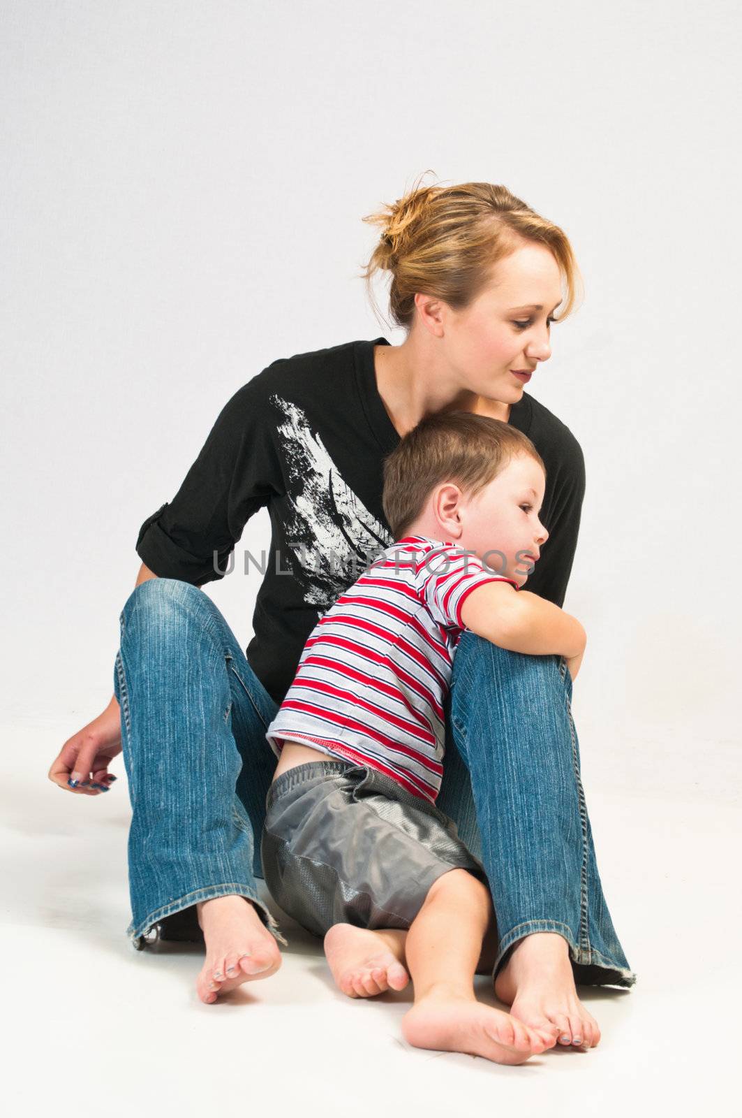 Pretty young woman with her son looking to her left while seated on the floor