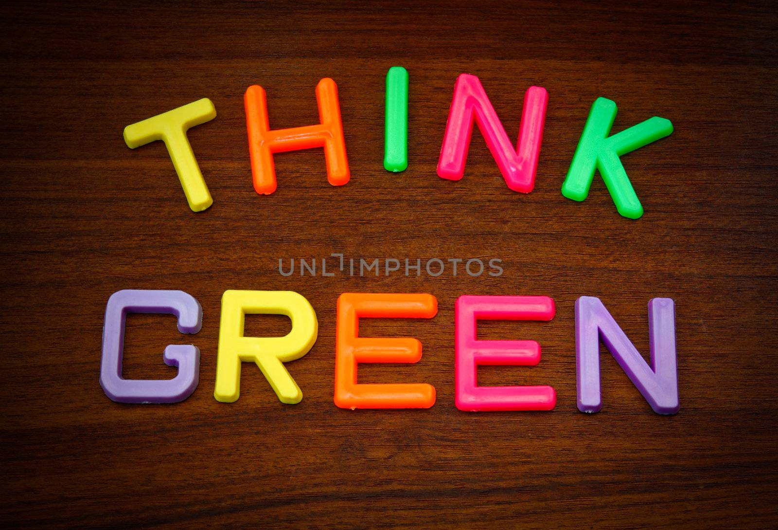 Think green in colorful toy letters on wood background