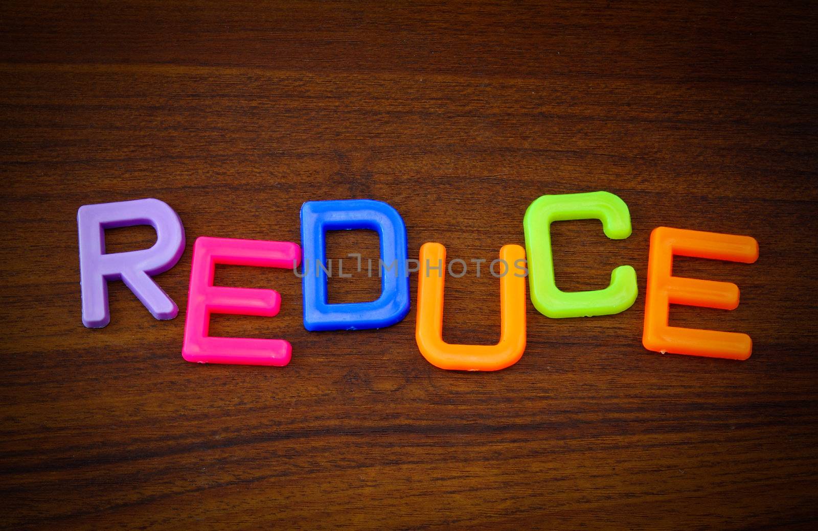 Reduce in colorful toy letters on wood background