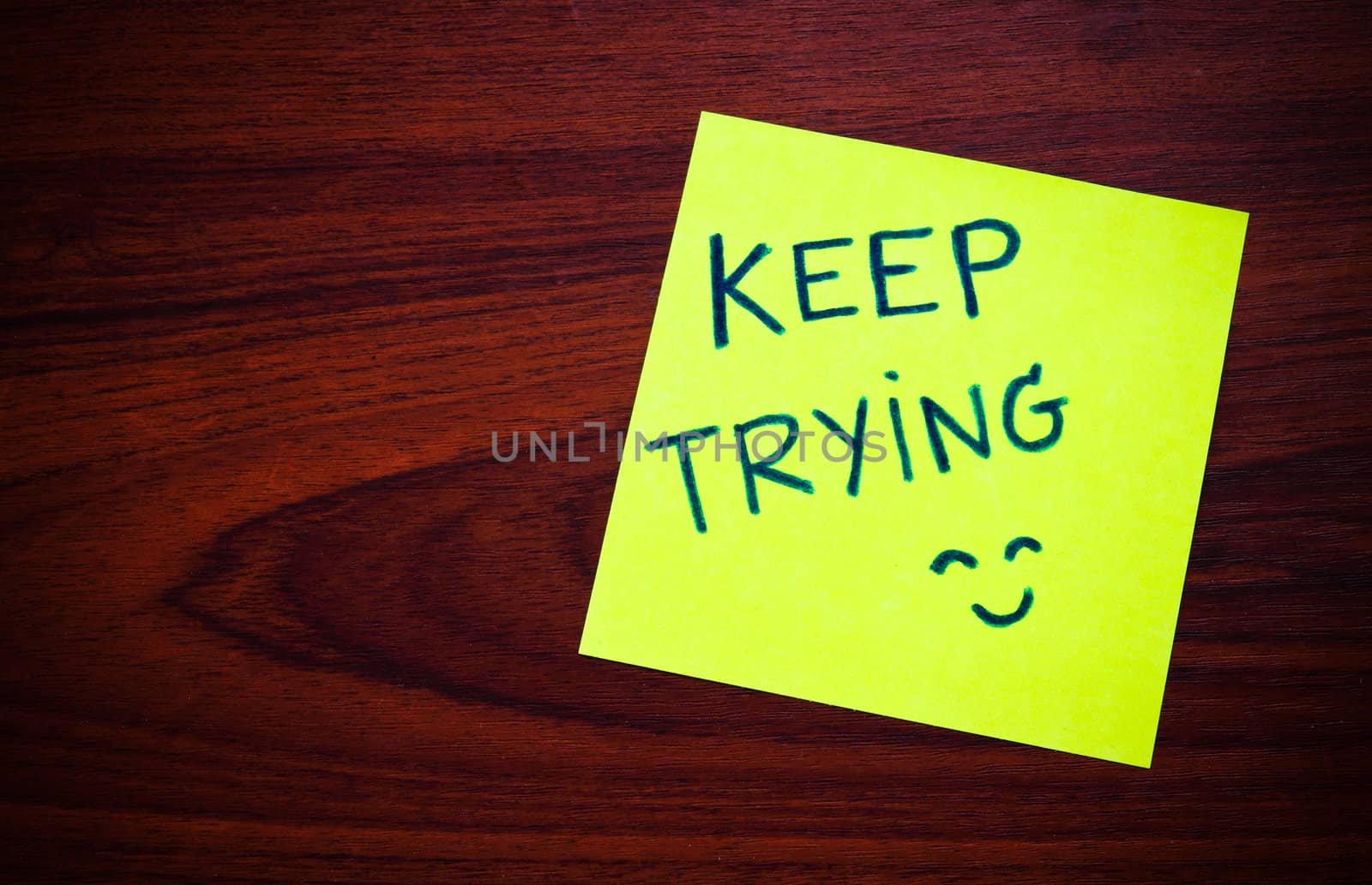 Keep trying on yellow sticky note against wood wall