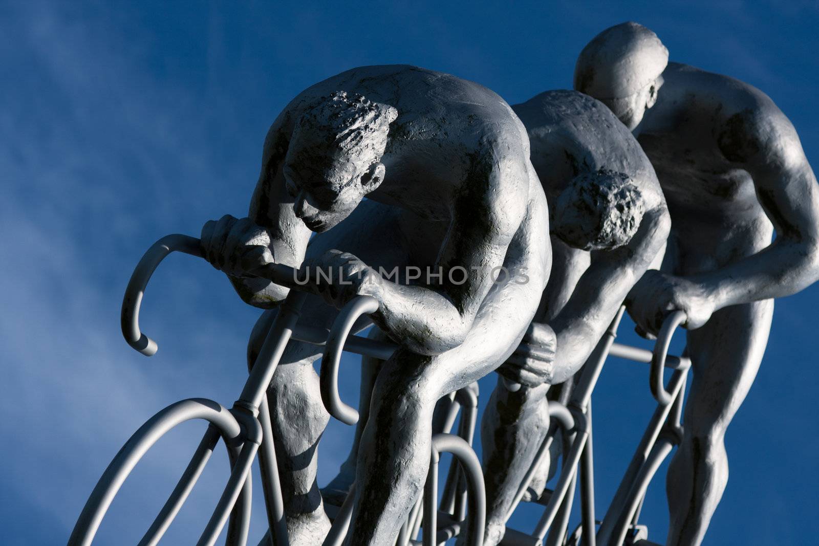Three cyclists rides  in a downhill, part sculpture