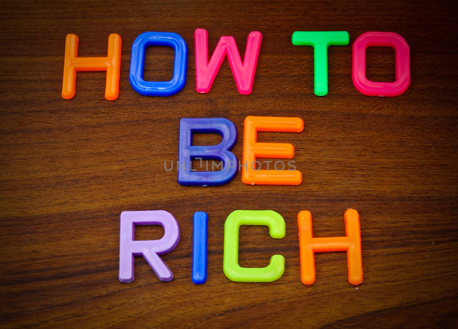 How to be rich in colorful toy letters on wood background  by nuchylee