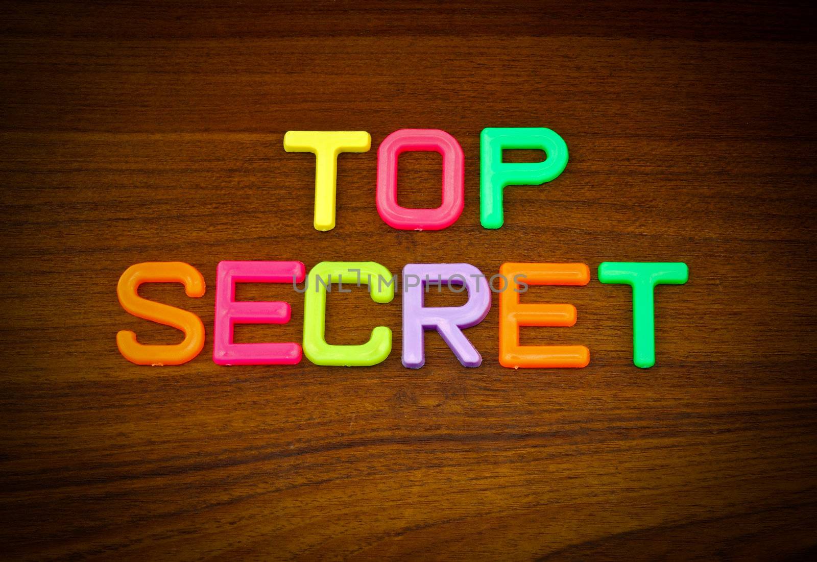 Top secret in colorful toy letters on wood background