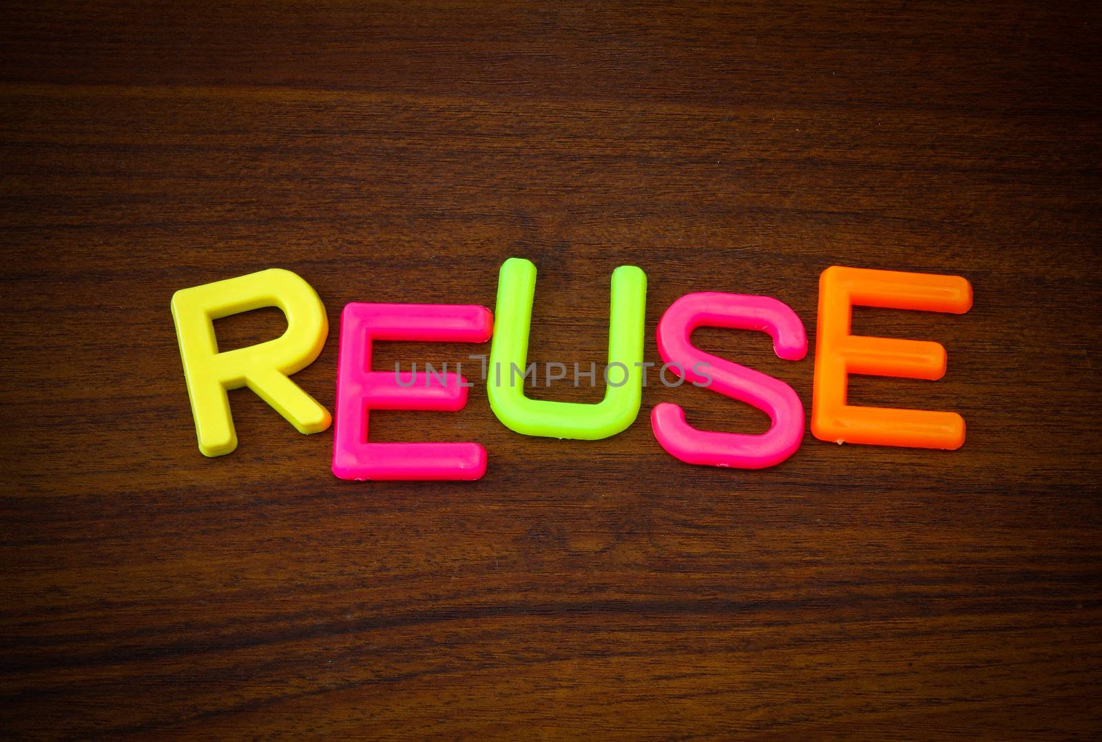 Reuse in colorful toy letters on wood background