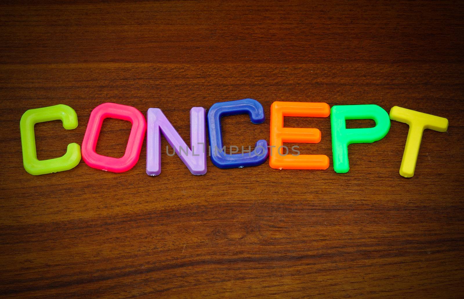 Concept in colorful toy letters on wood background