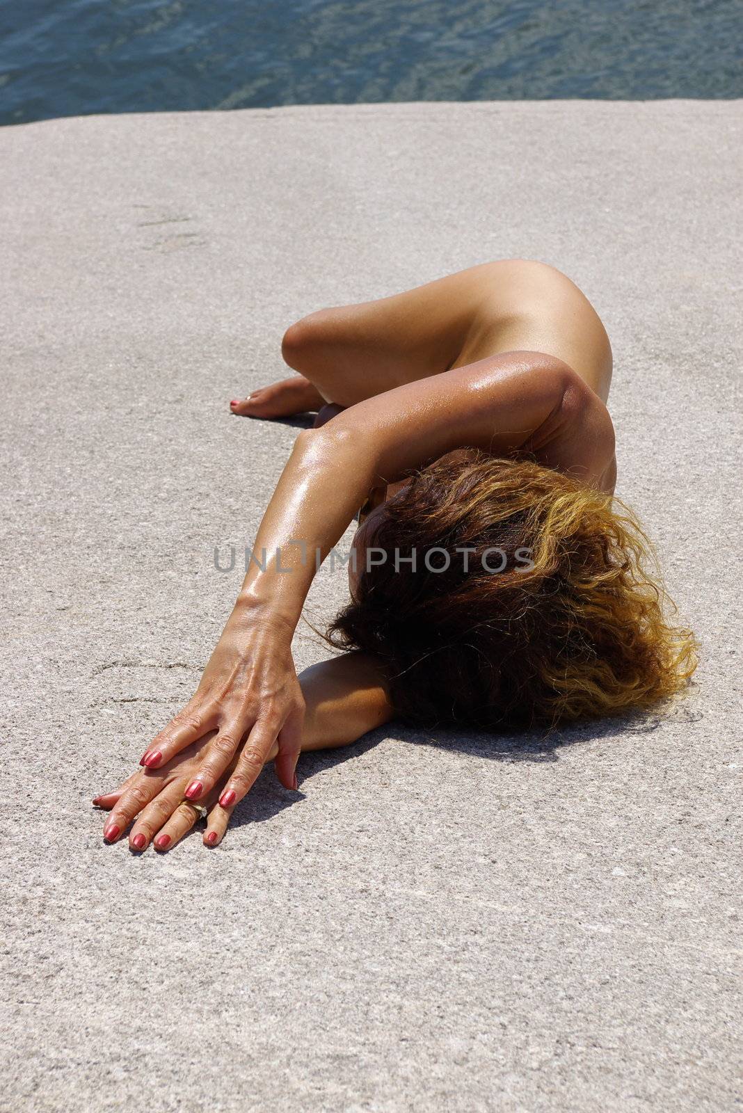Nude female model posing on a rocky beach