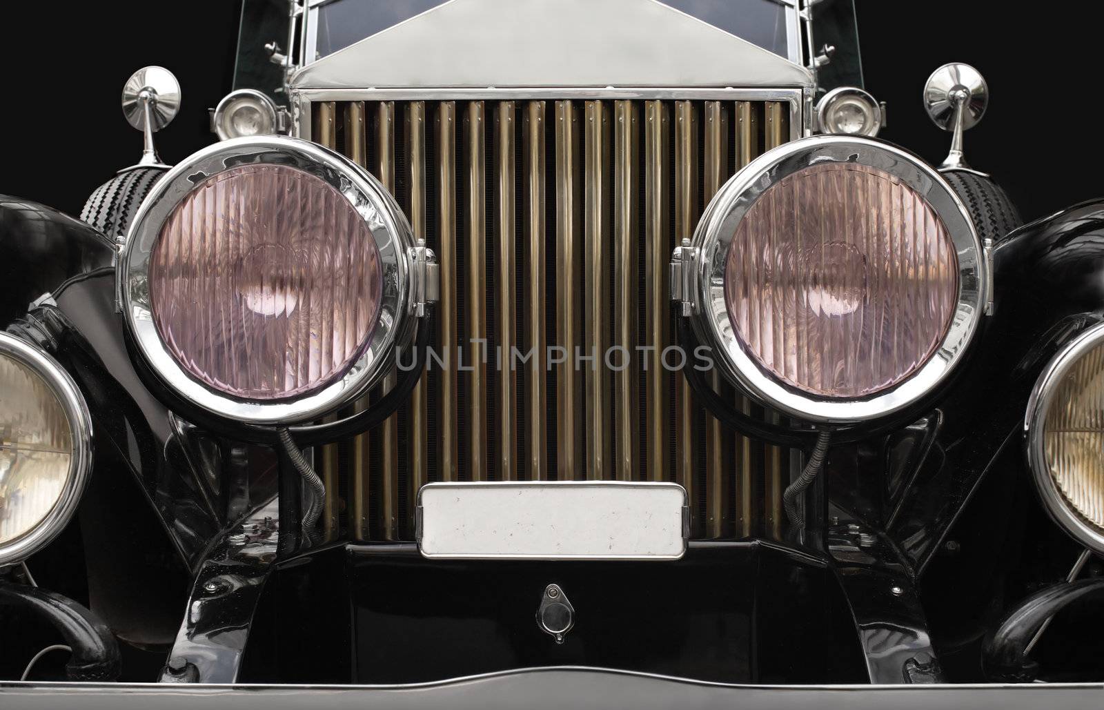 The grill and headlamps of an expensive antique classic car.  Slightly desaturated for more retro feel.  The pinkish tints in the headlight glass are normal and not added/altered.
