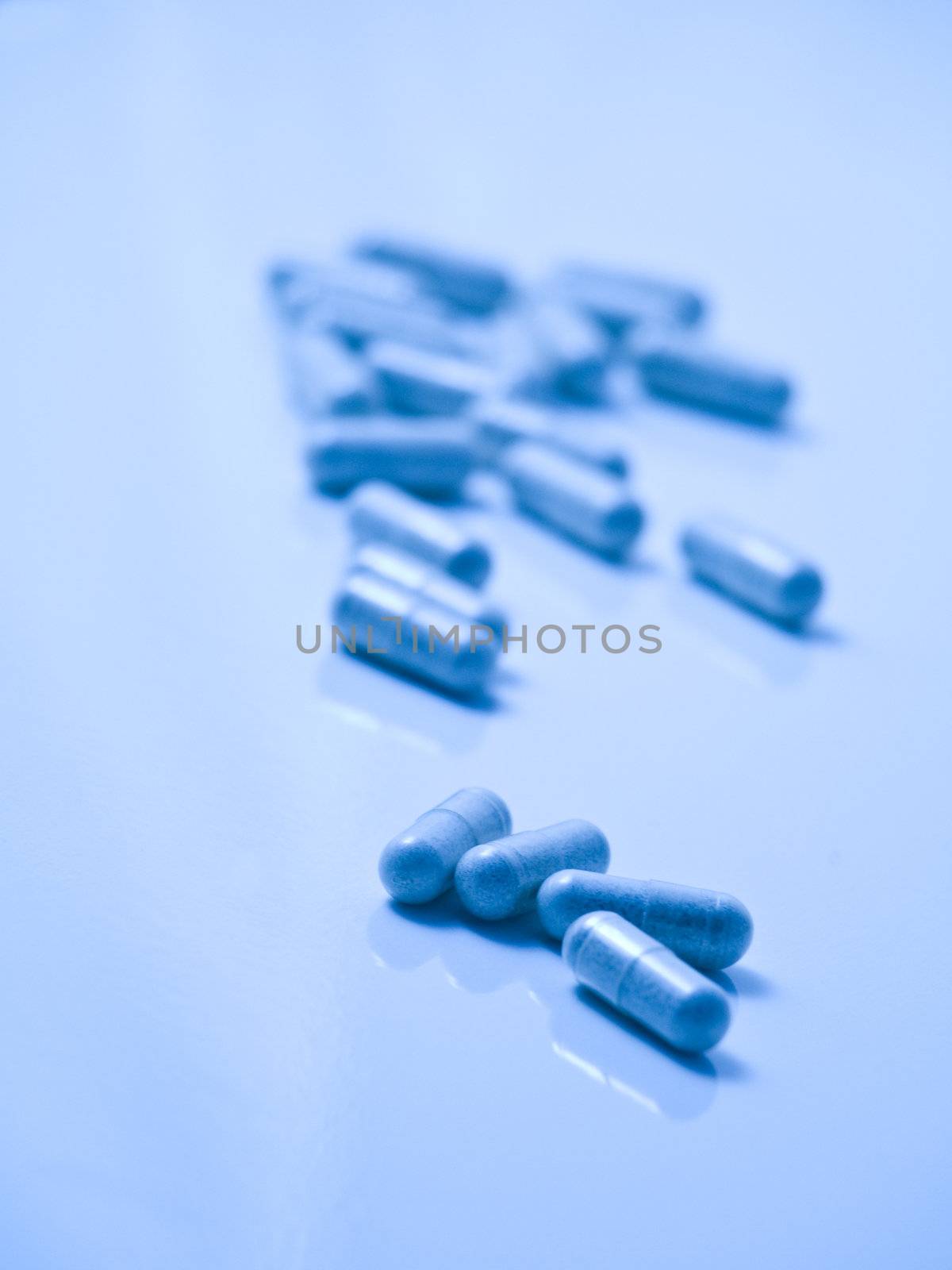 Blue tinted picture of  pills on reflective surface and with selective focus