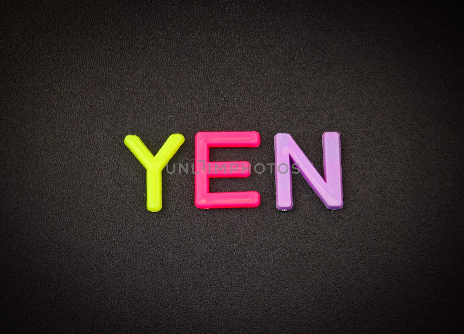Yen in colorful toy letters on black background