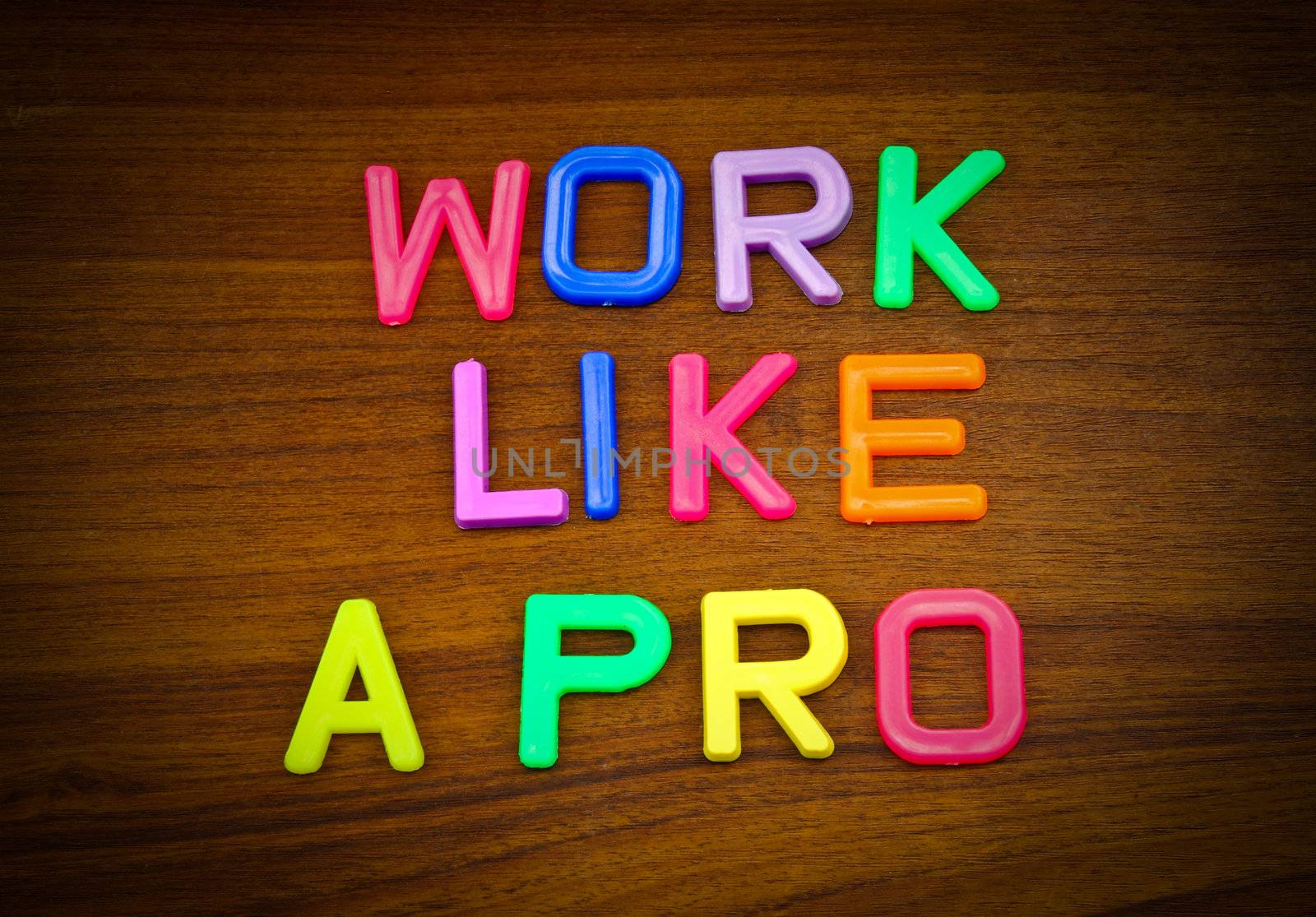 Work like a pro in colorful toy letters on wood background  by nuchylee