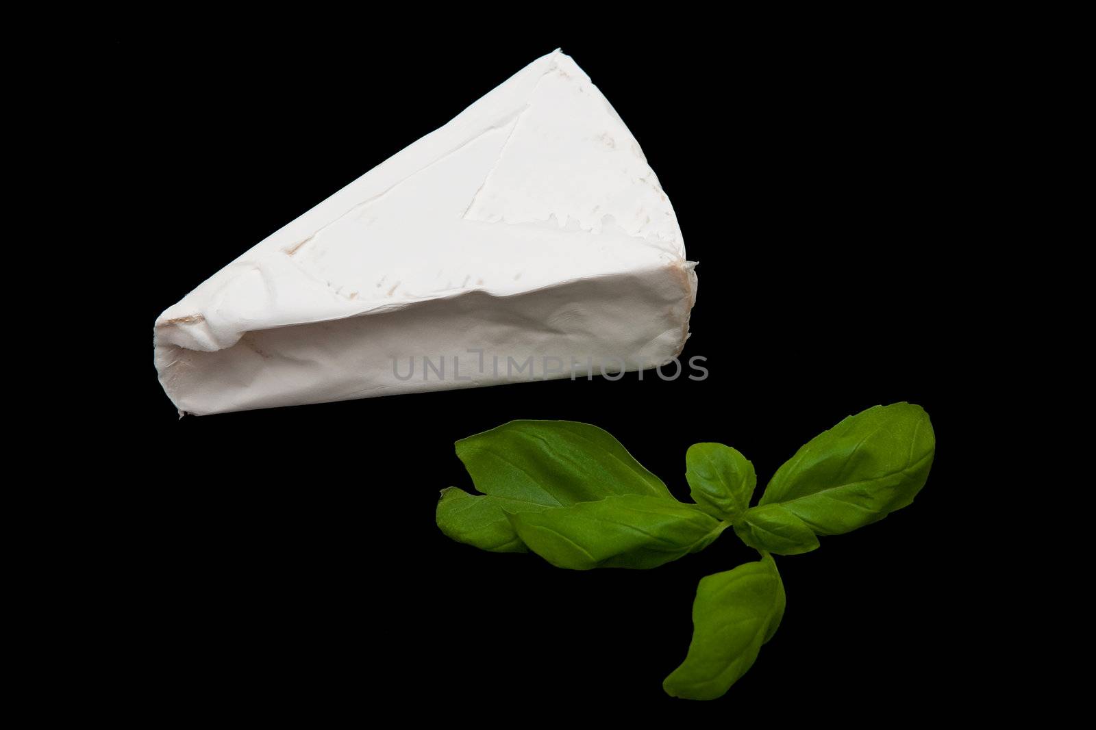 A blue cheese and fresh leaves of basil on the black