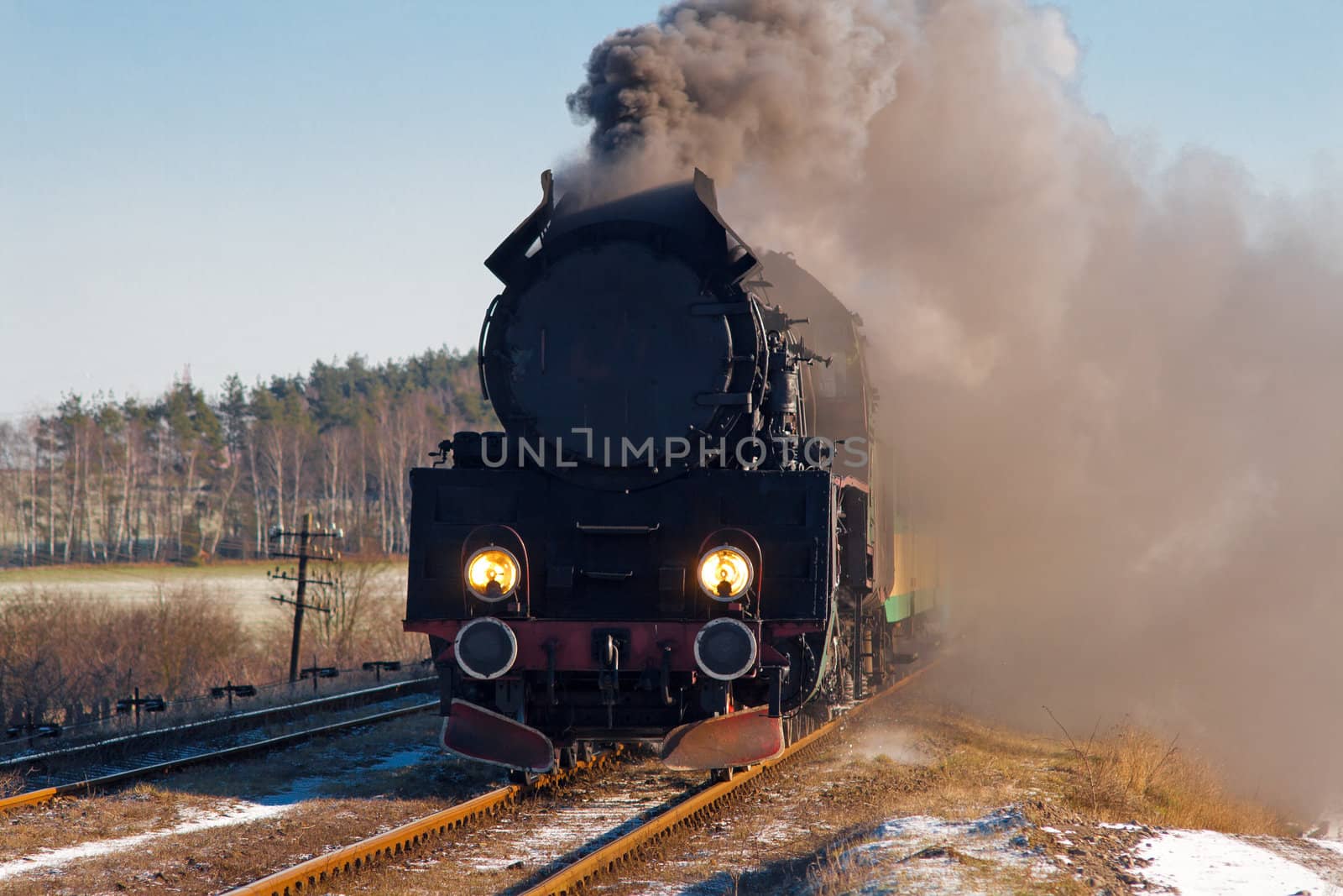 Vintage steam train passing through snowy countryside
