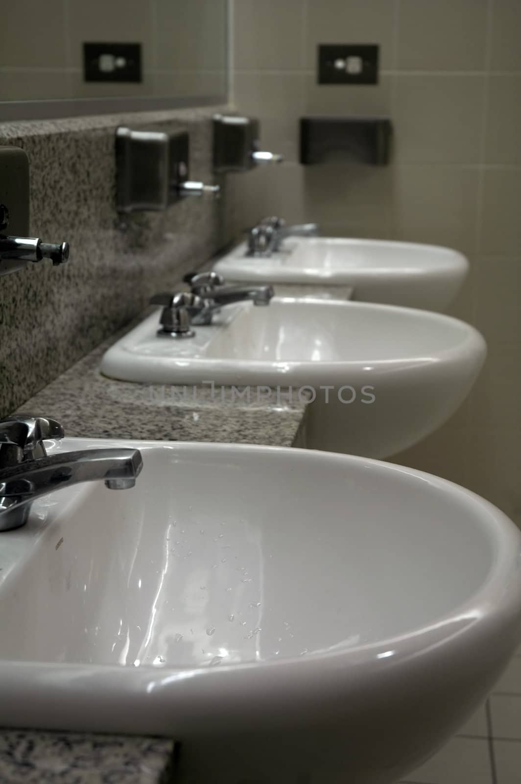three white sinks in public toilets, mirror on the wall