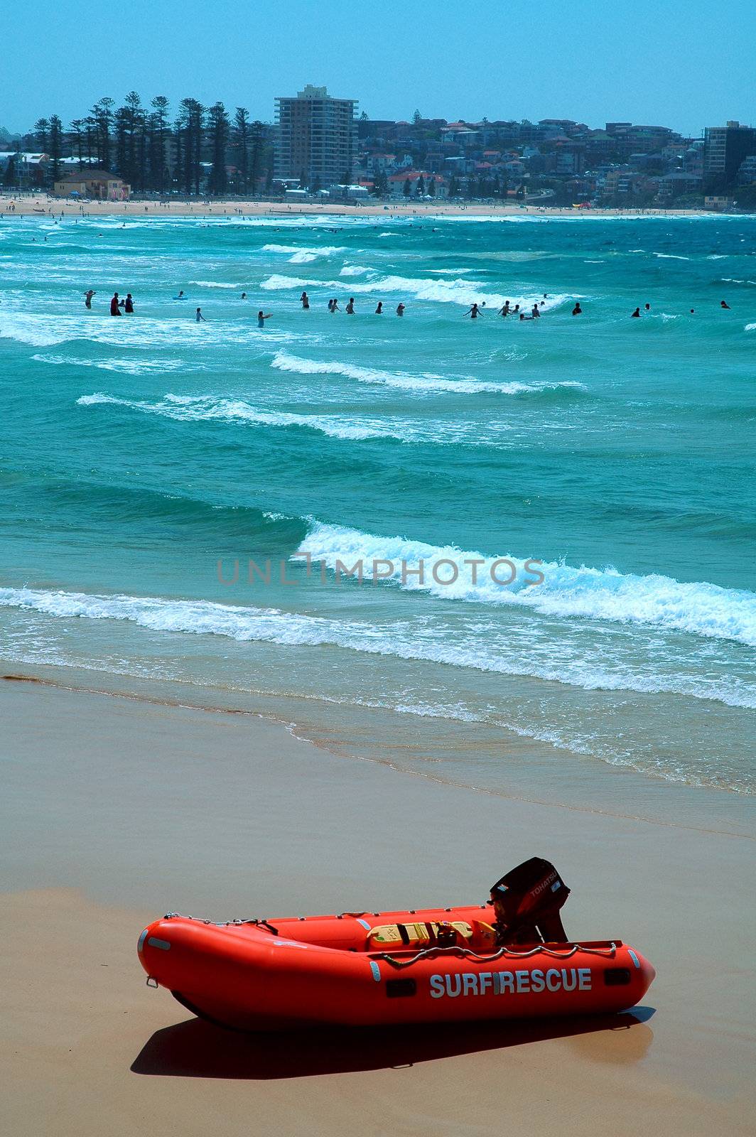 red boat with white sign: surf rescue, blue ocean in background