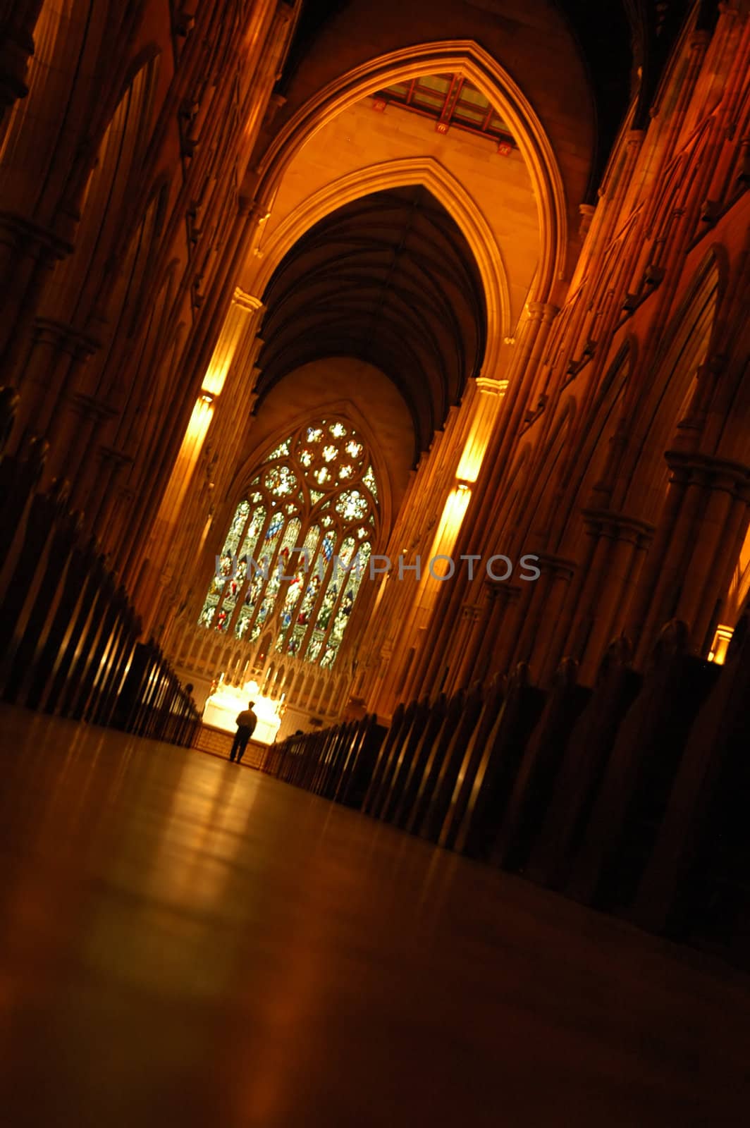 church interior, high ceiling, red lights, solitary man standing in front of altar