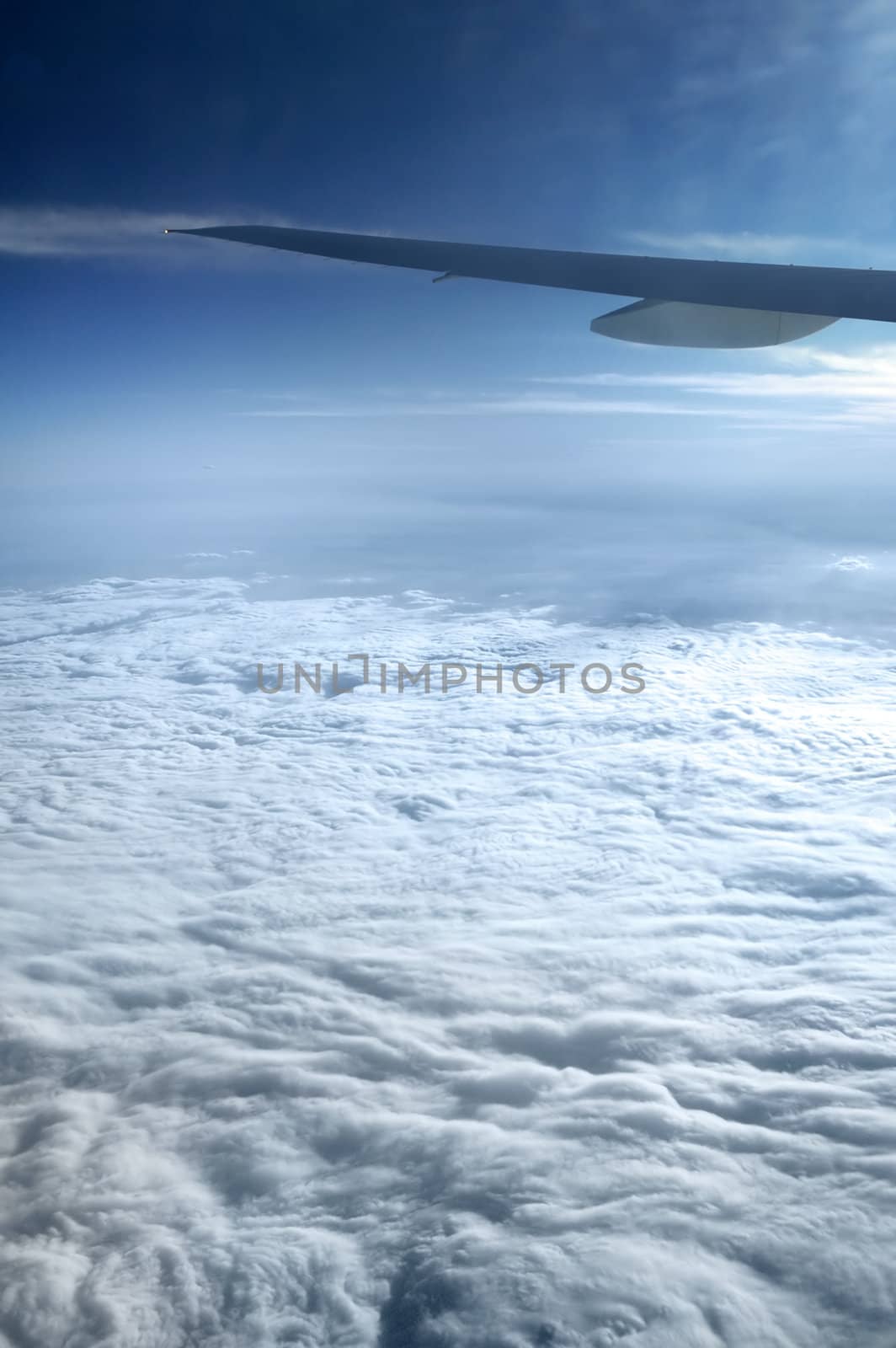 view from an airplane window, blue sky, clouds, end of blue wing