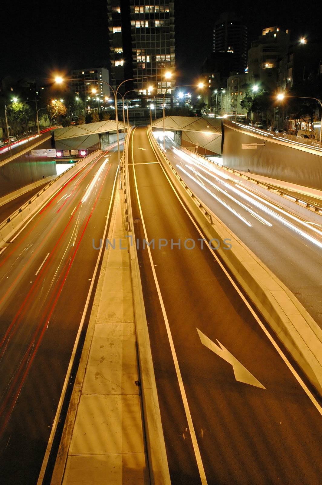 night tunnel traffic in sydney, blurred headlight trails, buildings in distance, 