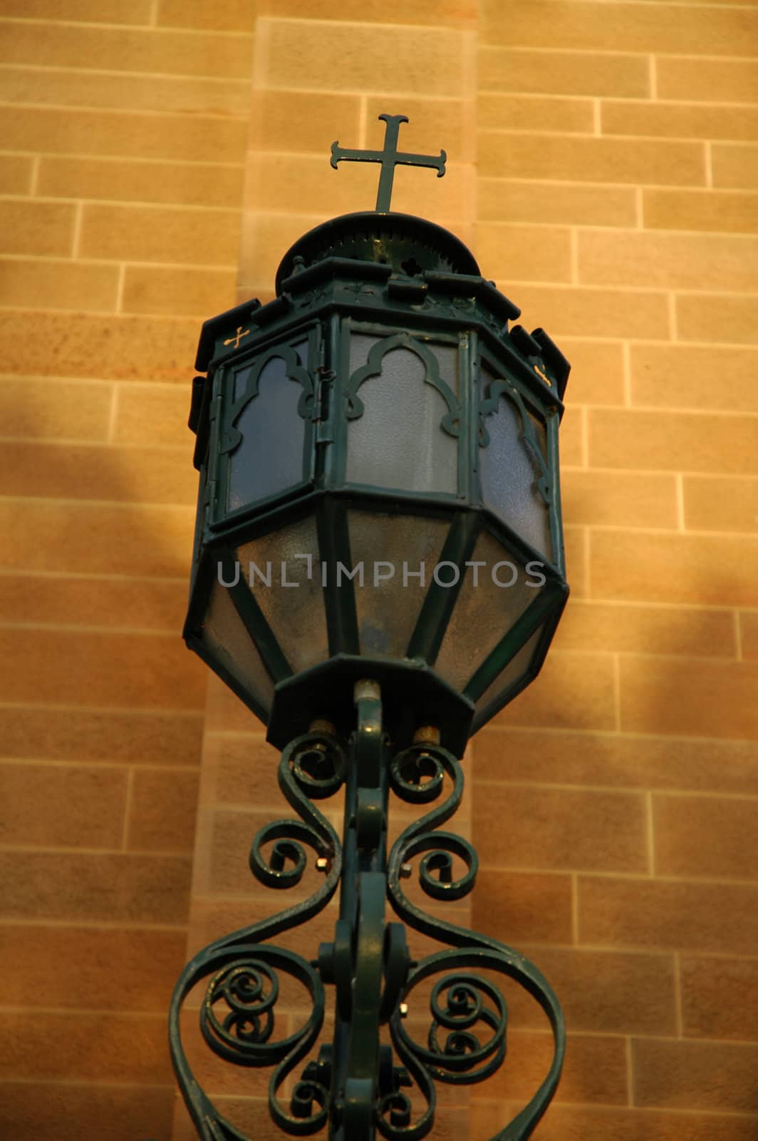 old steel lantern with cross on top of it, brick wall in background, part of a church in sydney