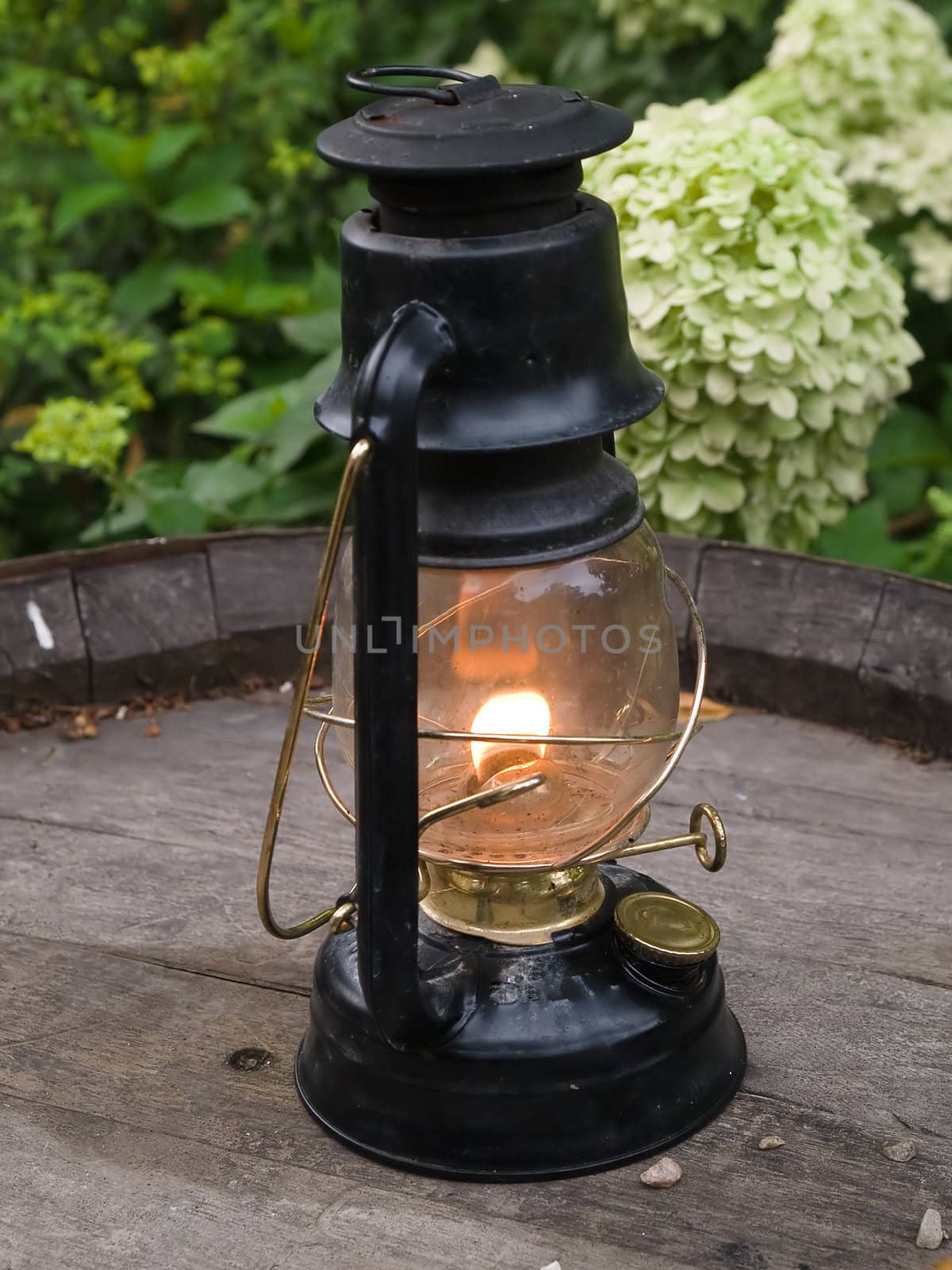 Classical nautical oil lamp burns on a wooden barrel outdoors
