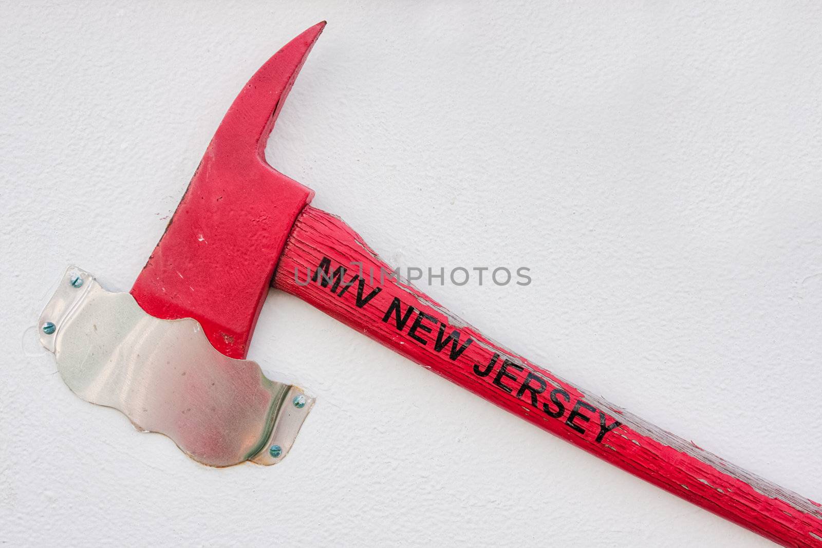 A red axe hanging on a white wall