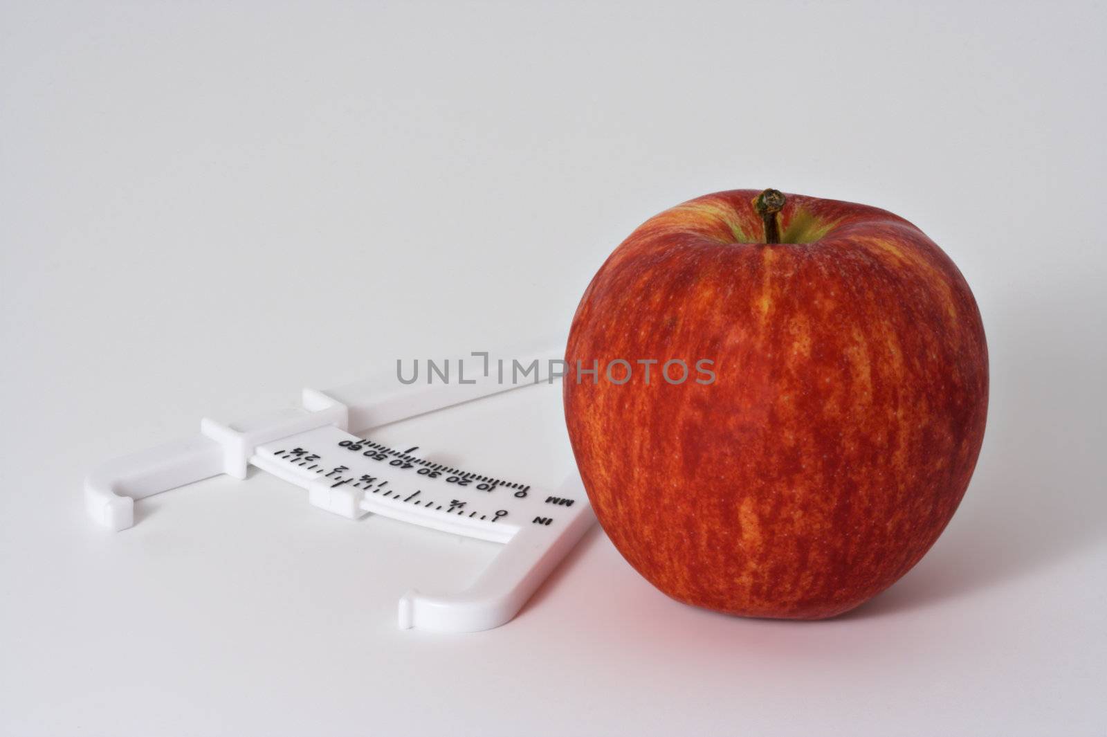 Apple and fat calipers on white background