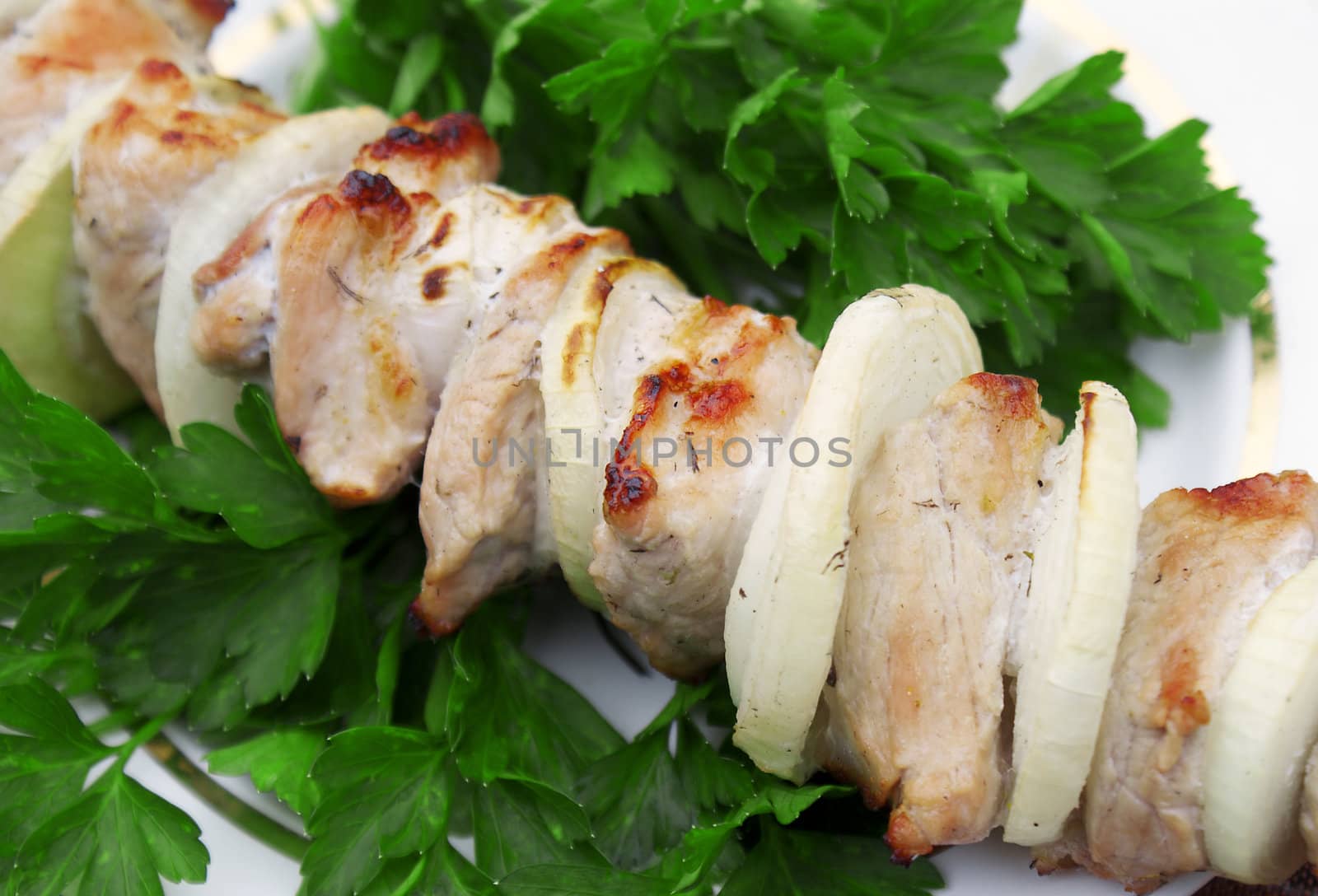 Appetizing juicy shish kebab from fresh pork in green leaves of parsley