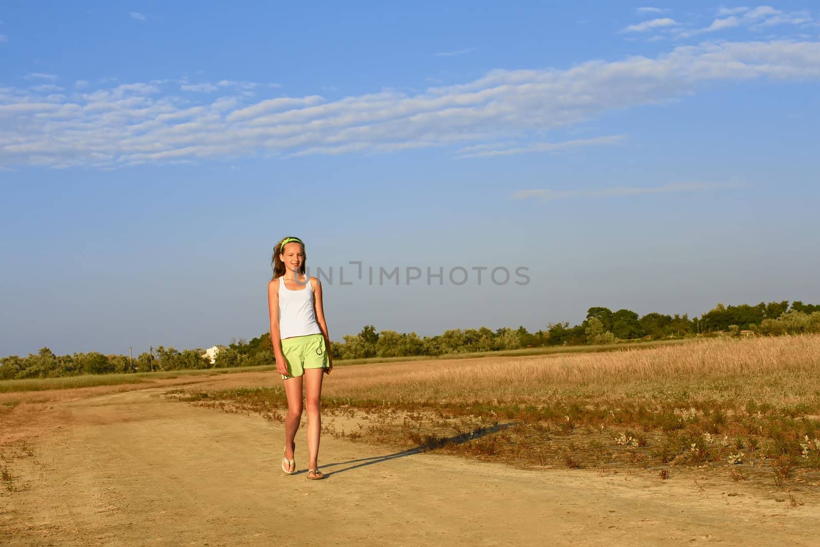 Teenage girl walking on the sandy village road. Summer heat. Kinburn Spit near Ochakiv, Ukraine
