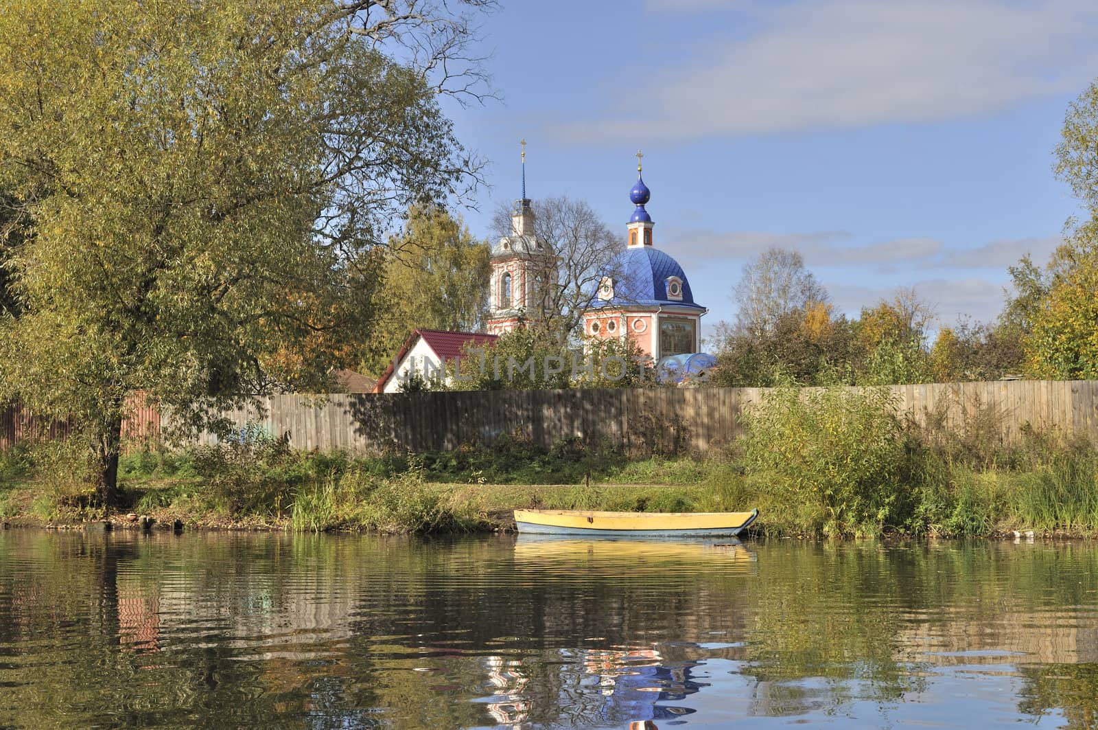 River bank with yellow wooden boat and church on background in Pereslavl-Zalessky, Russia