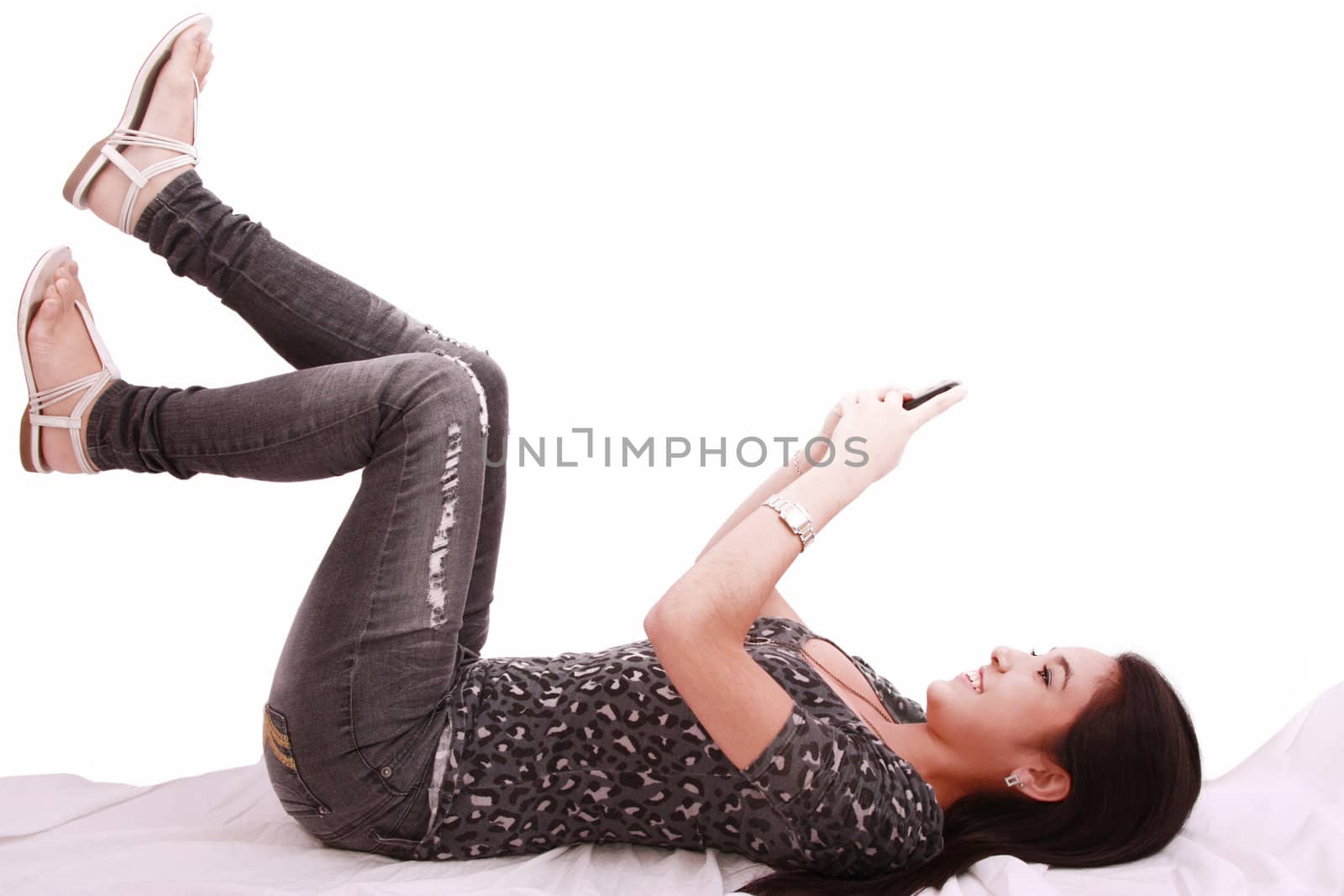 beautiful young girl laying on a pillow chatting on a cell phone by dacasdo